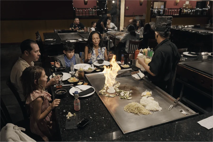 Family watching the hibachi chef light the grill at their table at Mahzu East Windsor