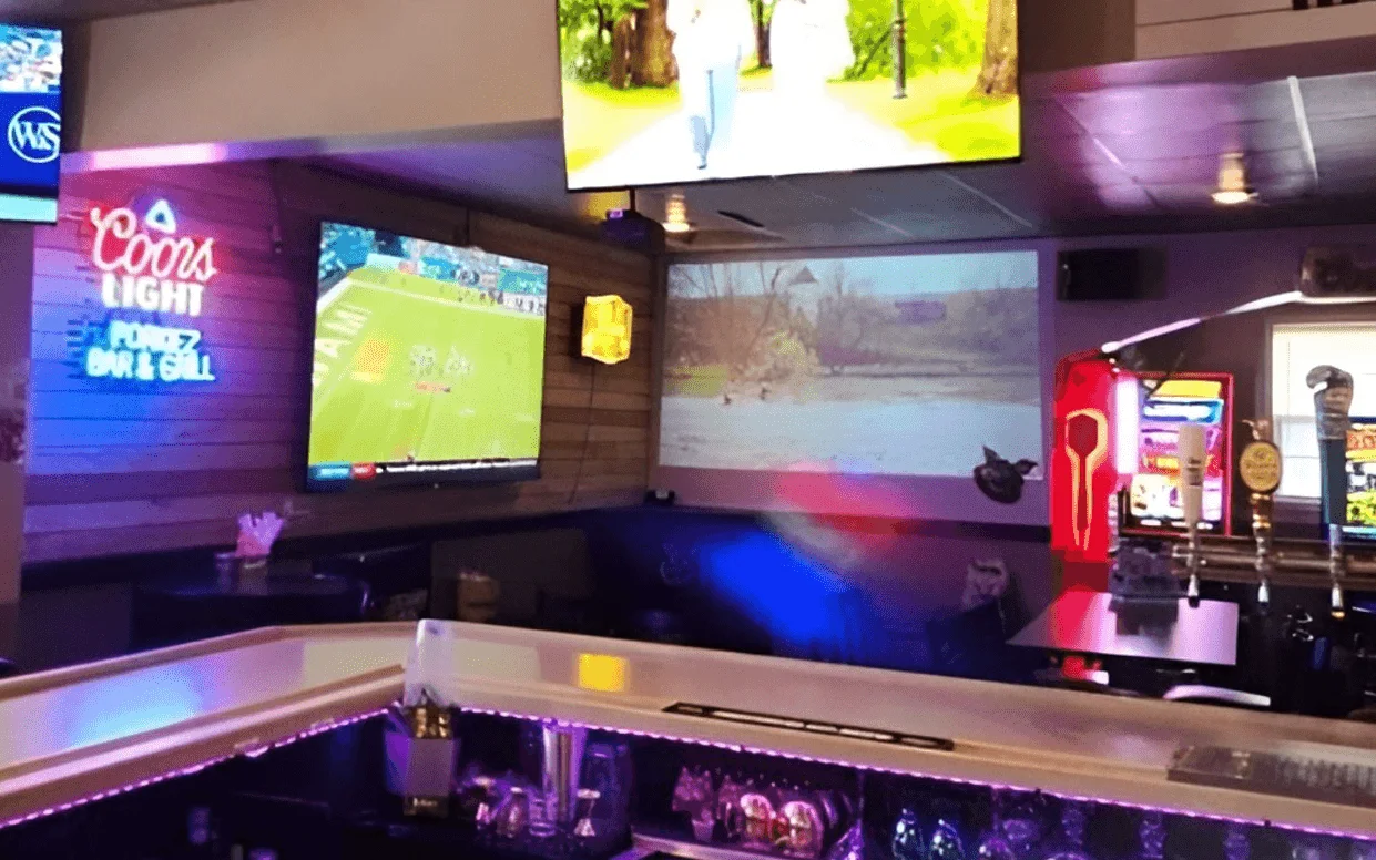 Modern bar interior with multiple screens and vibrant lighting