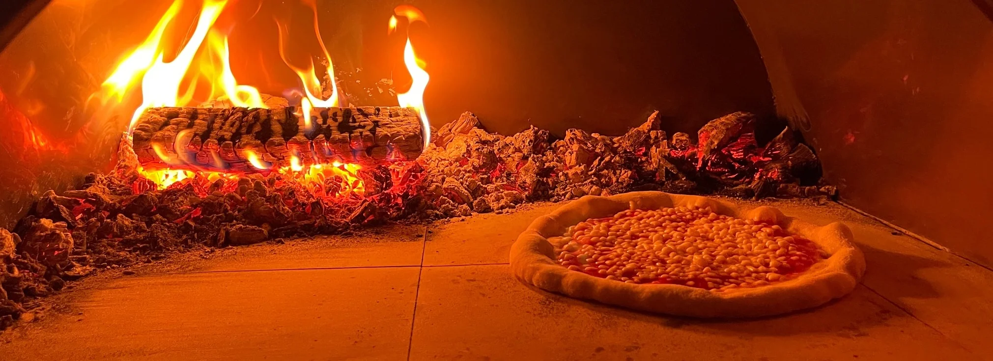 Margherita pizza baking in a wood-fired oven