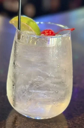 A refreshing glass of white sangria with fruit garnishes.