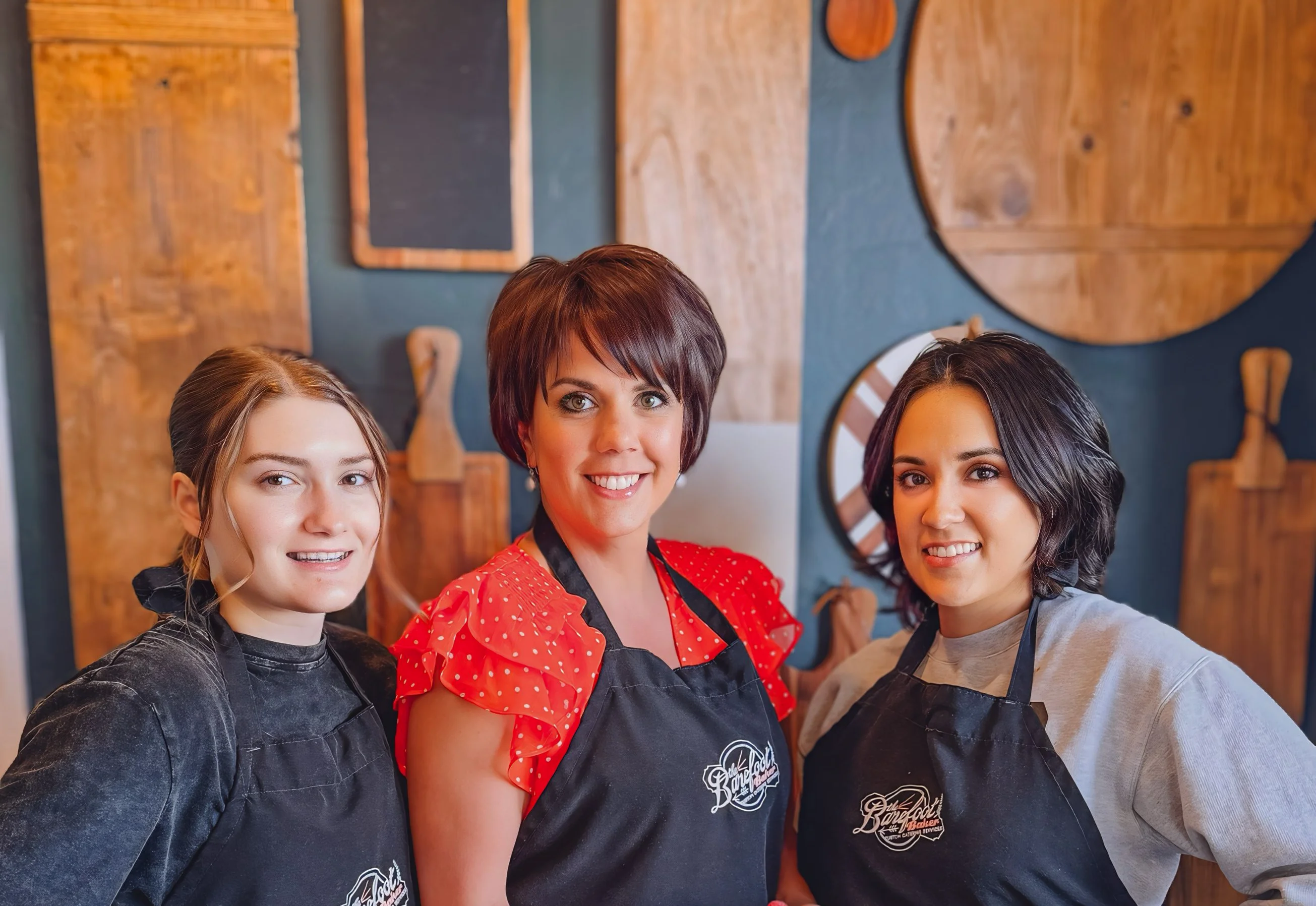 Three bakers proudly displaying decorated cupcakes in a cozy kitchen