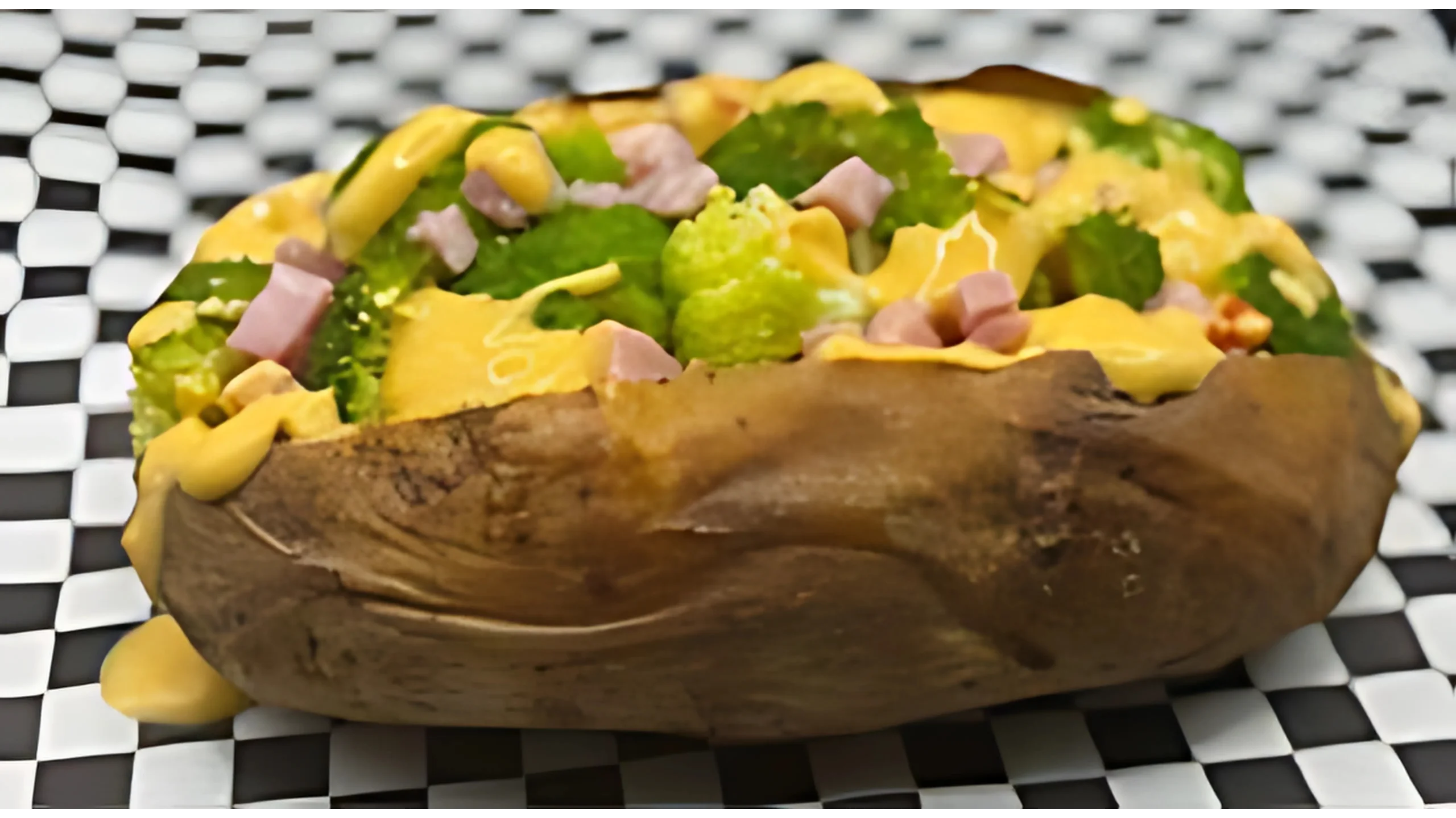 A loaded baked potato with broccoli and ham and cheese