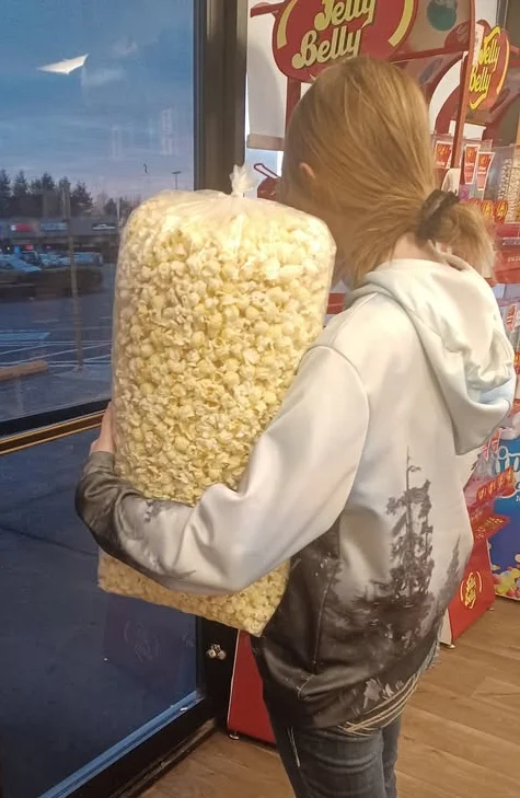 Person holding a large bag of popcorn at a store entrance