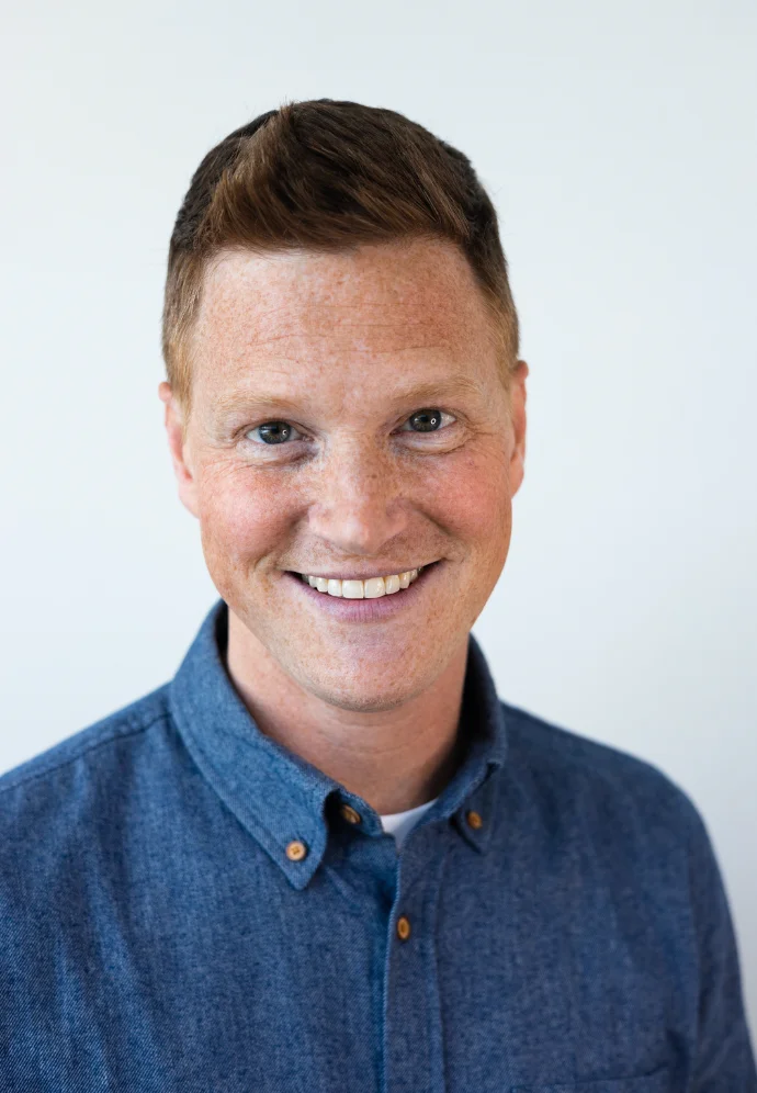 Smiling man in a denim shirt against a plain background