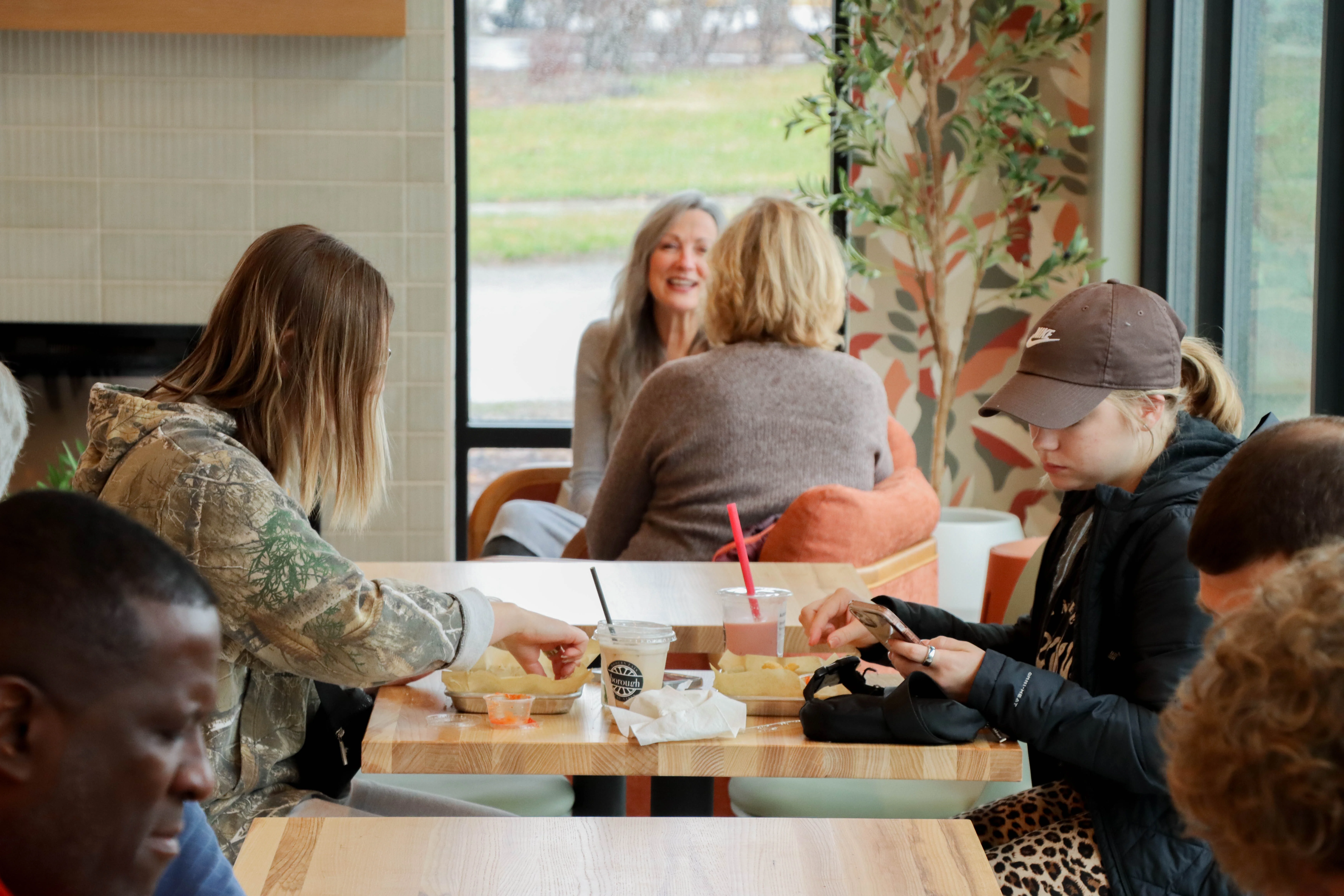 Two people with food on the table eating in The Borough, with Two older woman talking that you can see past them