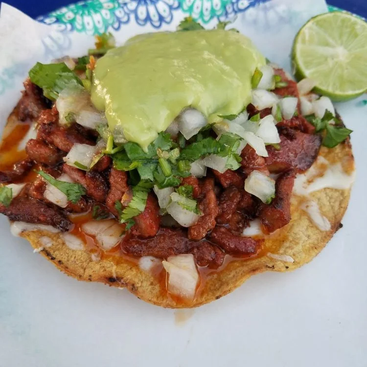 A high quality made vampiros, which is melted cheese topped with meat, onion, and guacamole on crunchy tortilla