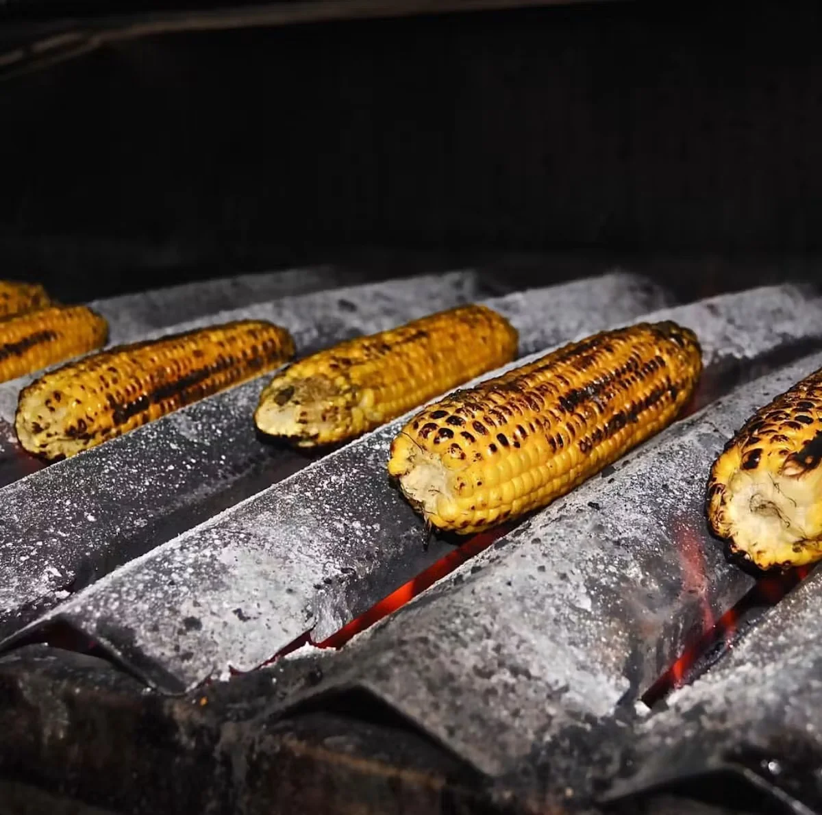 Grilled Mexican elote corn on the cob over charcoal