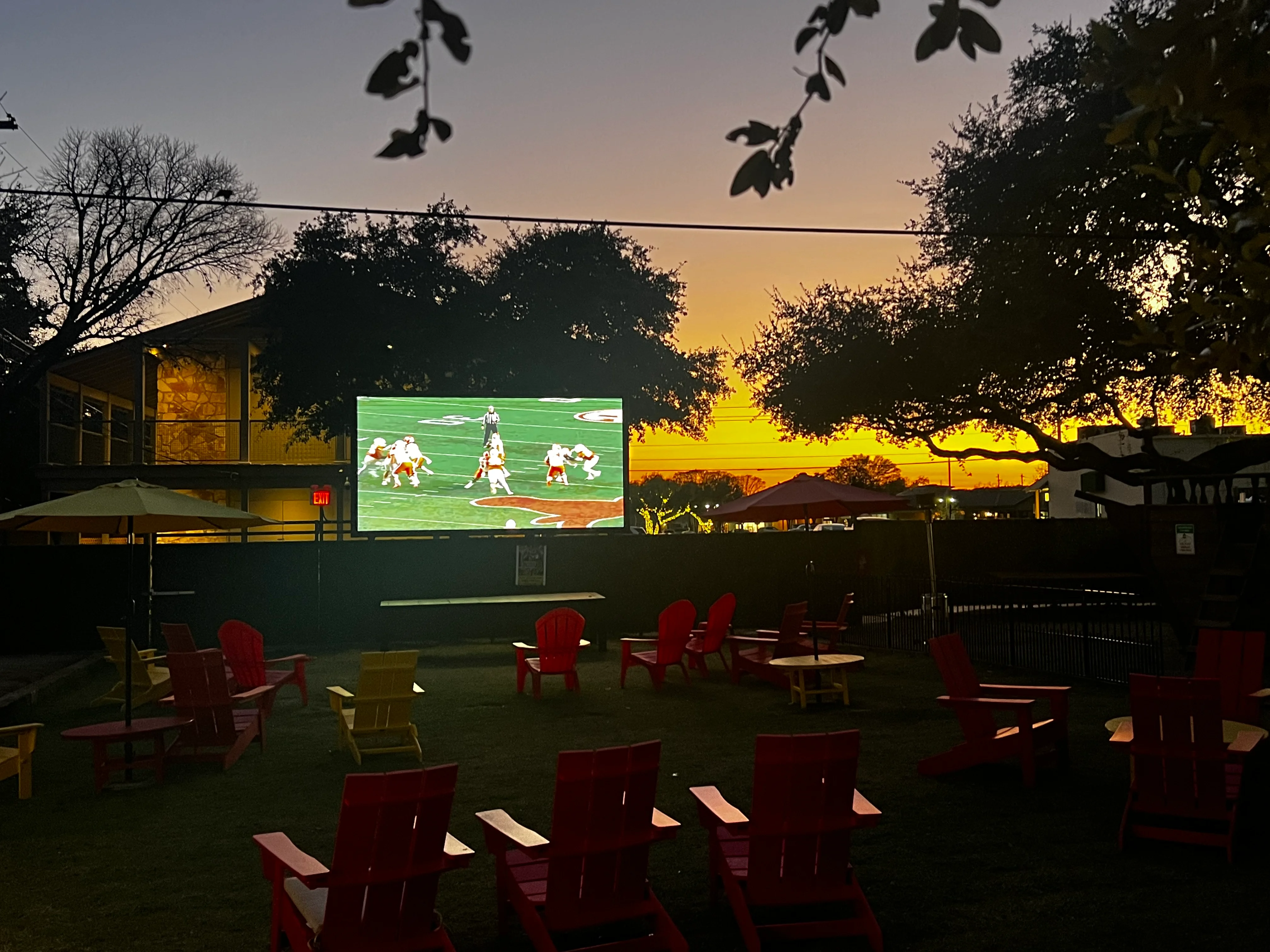 Outdoor seating area with a large screen and sunset view