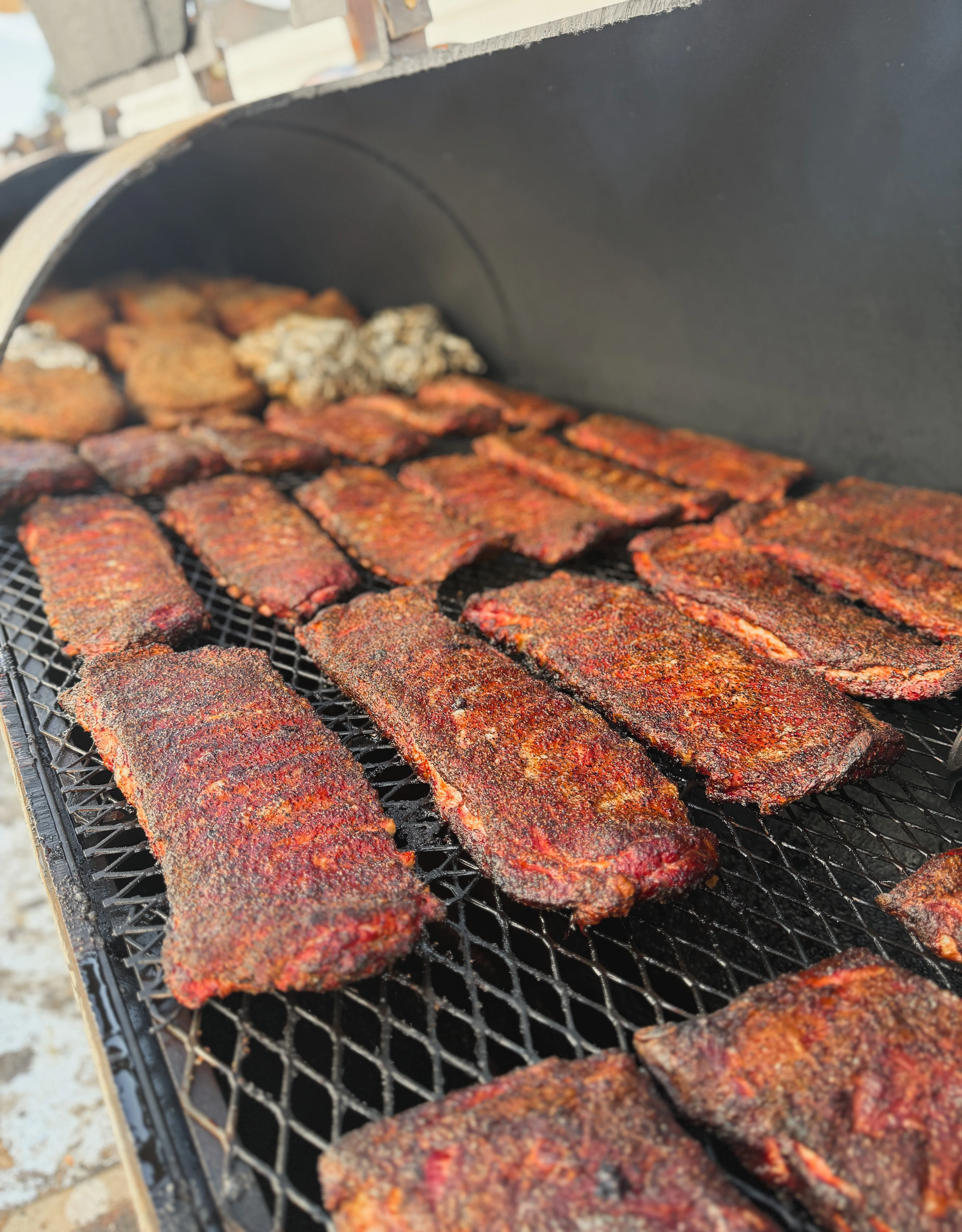 Smoked barbecue ribs on a grill, showcasing a rich, smoky crust