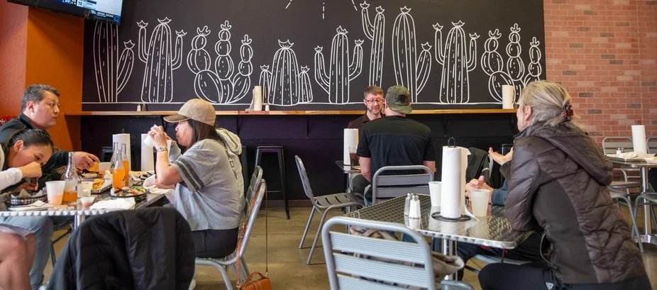 Cozy dining area at Taco Empire with cactus mural and TV