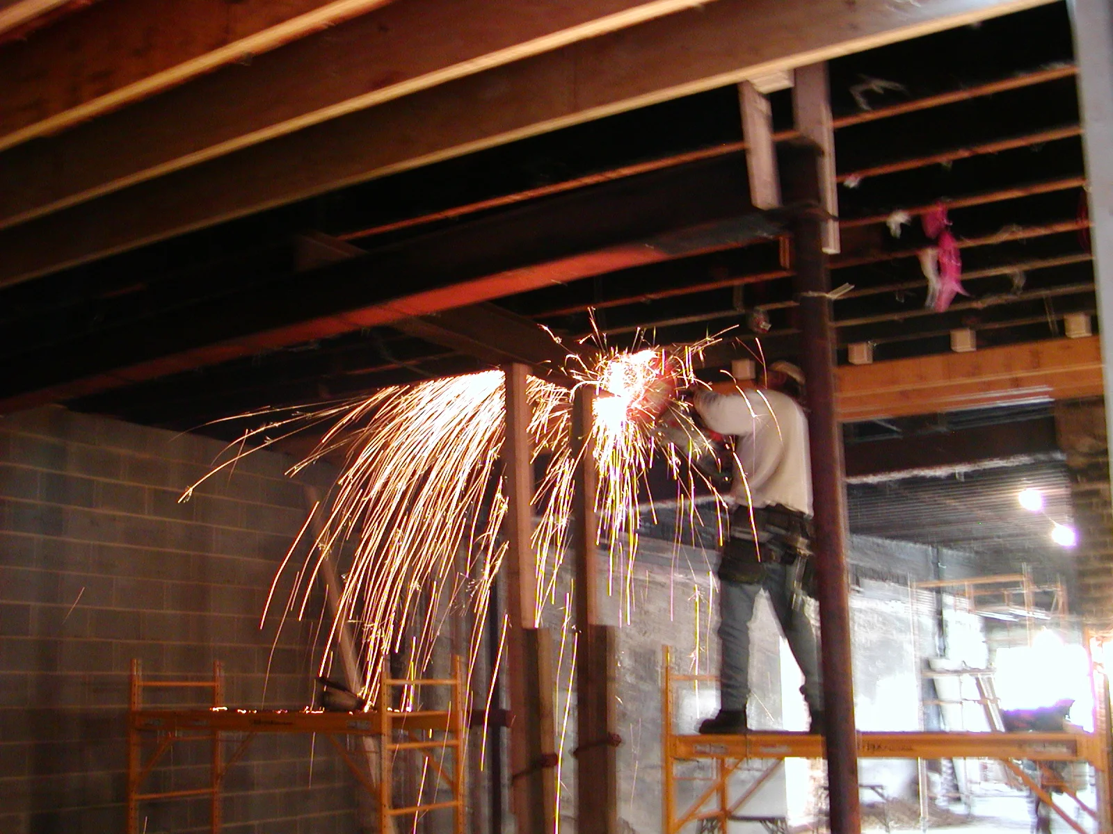 Construction worker welding steel beams with sparks flying in a renovation site
