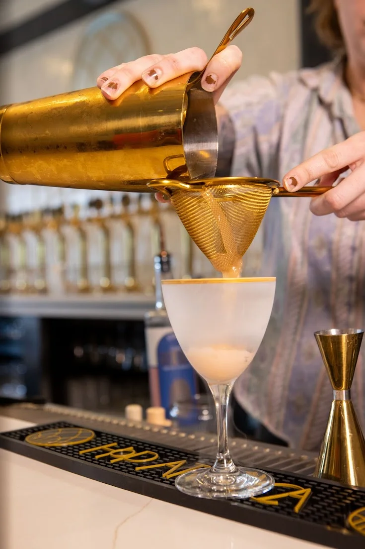 Bartender pouring a cocktail through a strainer