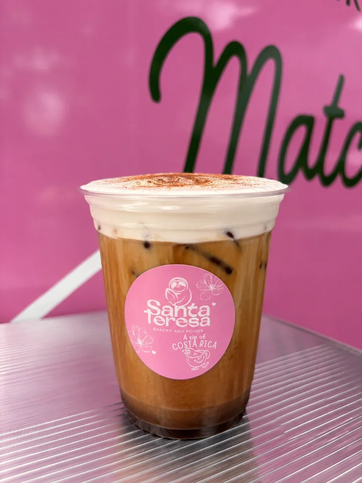 A creamy iced coffee drink in a clear cup, featuring a frothy top and a smooth caramel-like base.