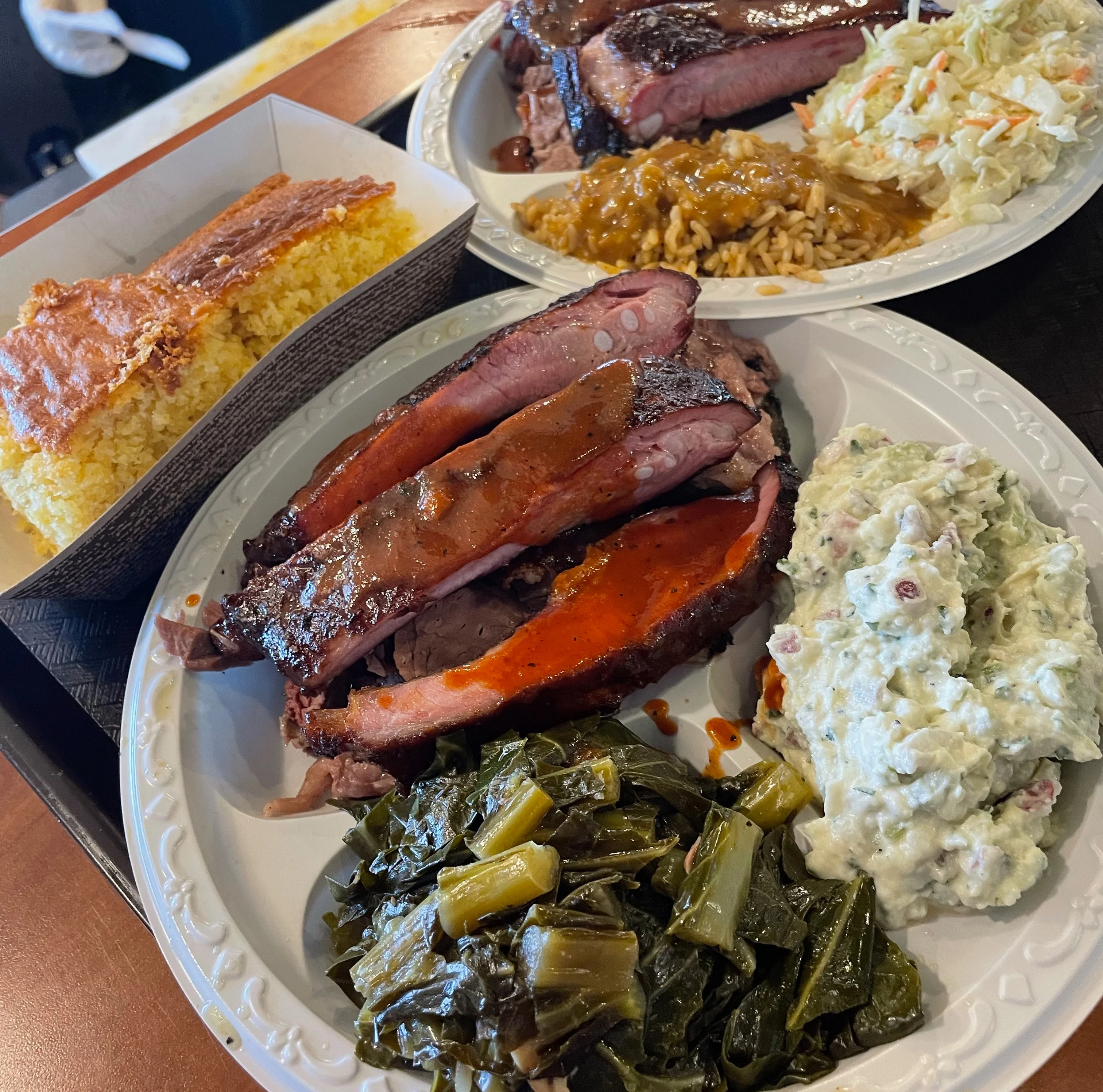 Plate of ribs with collard greens, potato salad, and corn bread
