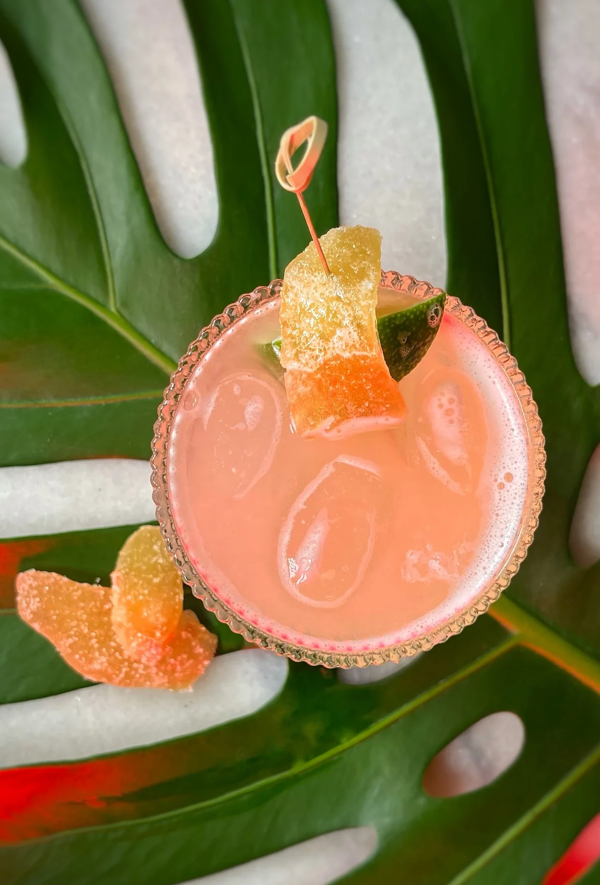 Colorful tropical cocktail garnished with fruit on a green leaf