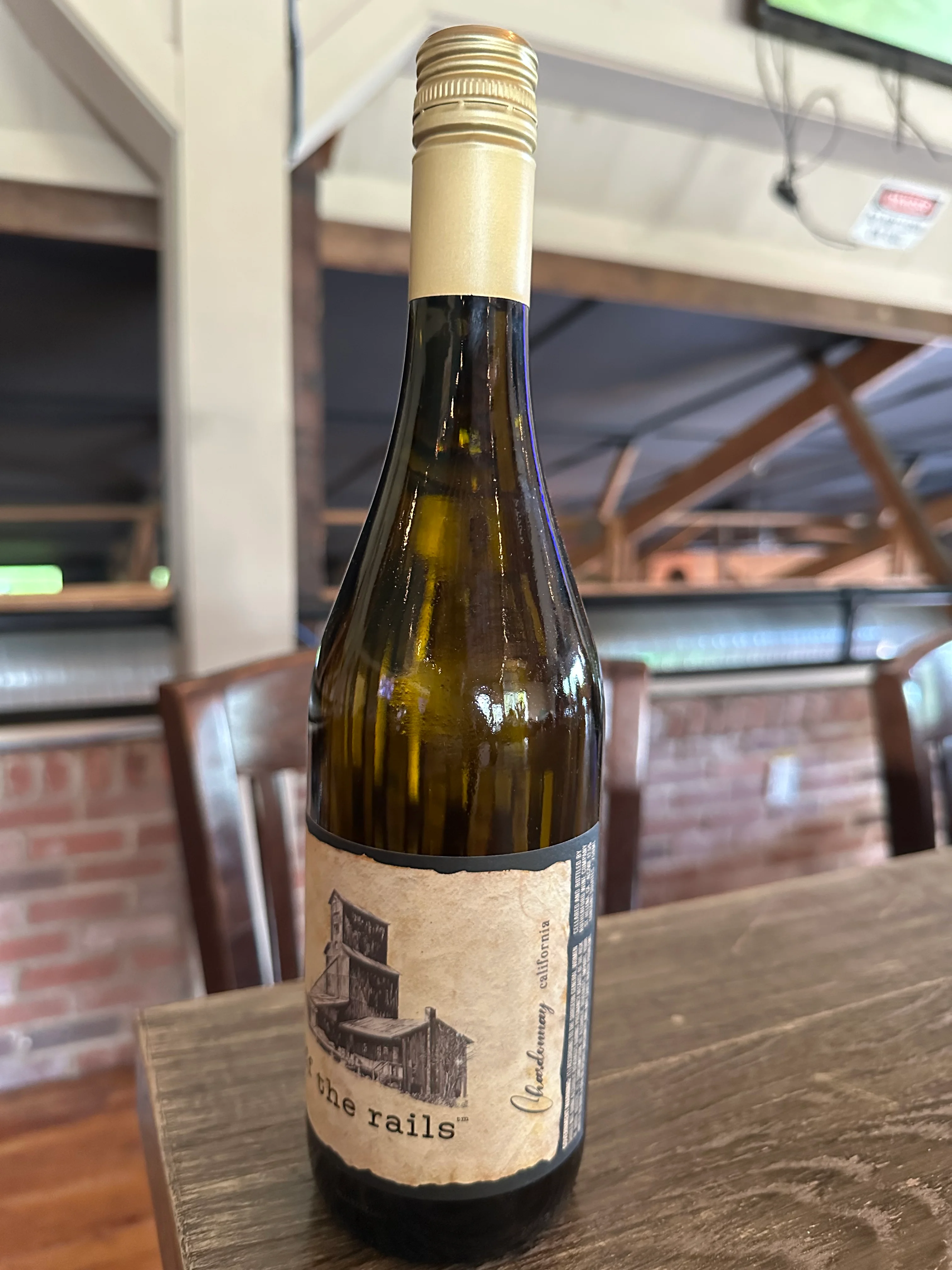 A bottle of Chardonnay displayed on a wooden table, showcasing its label and cork top.