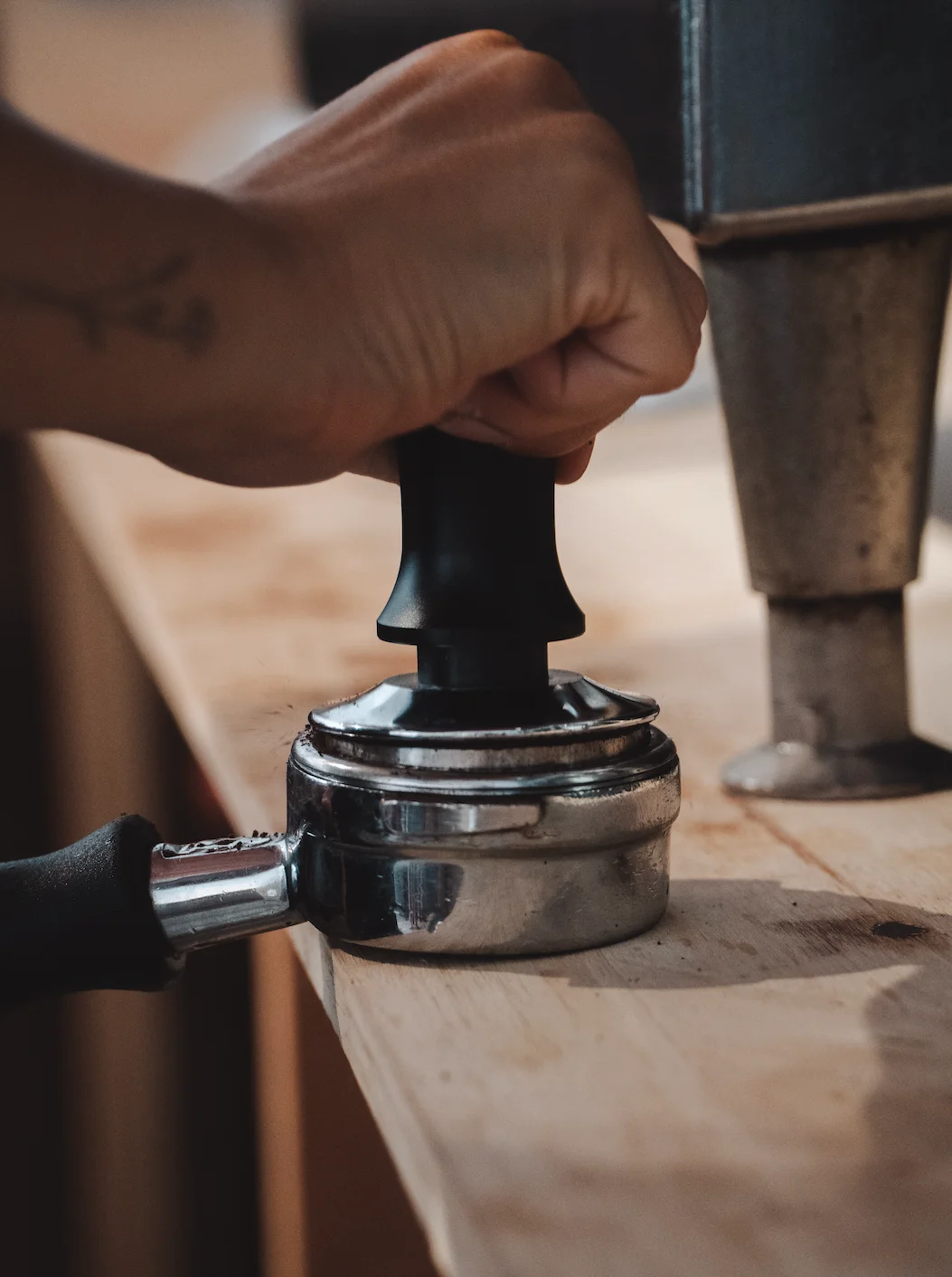 Barista tamping coffee grounds for espresso preparation