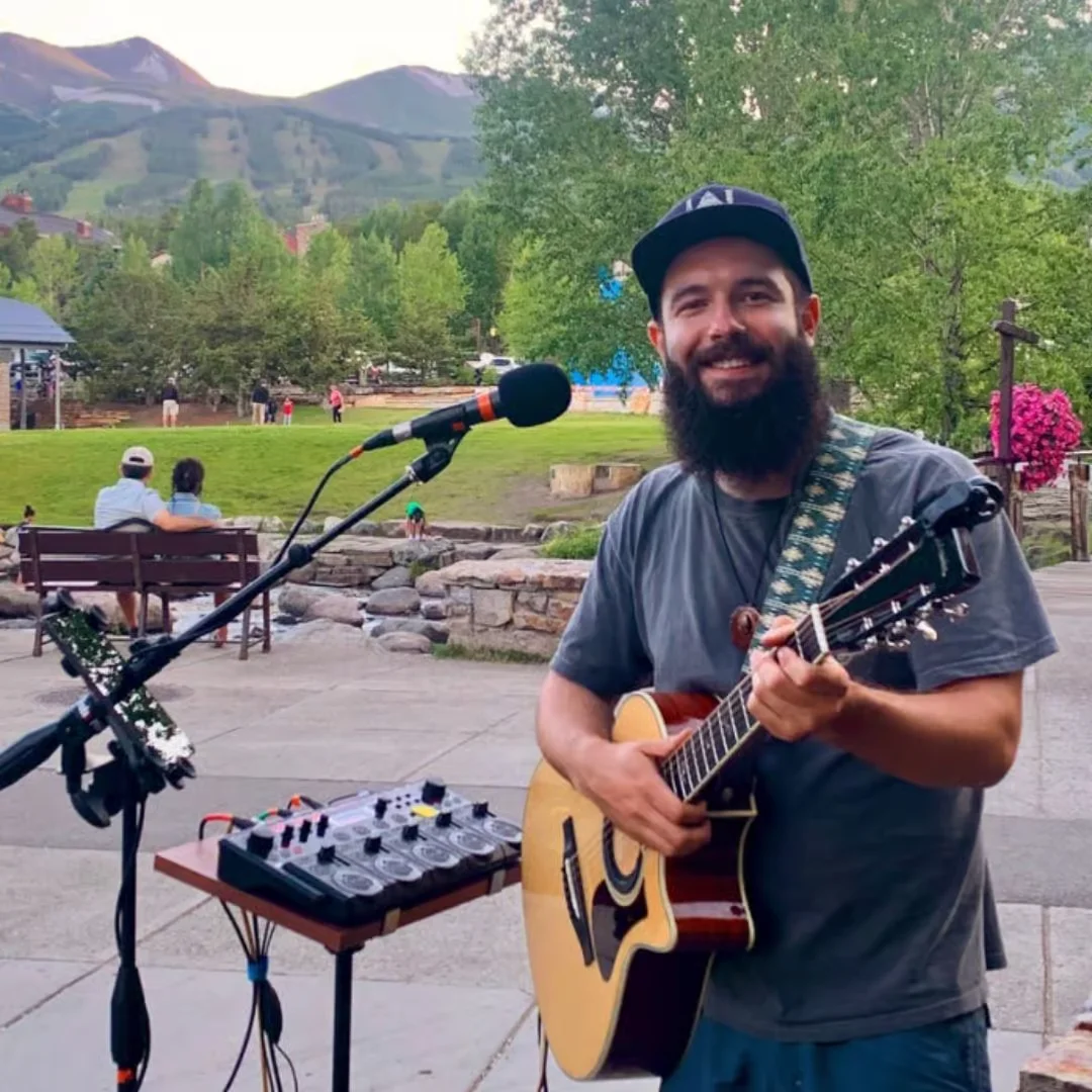 Musician performing outdoors with mountains in the background