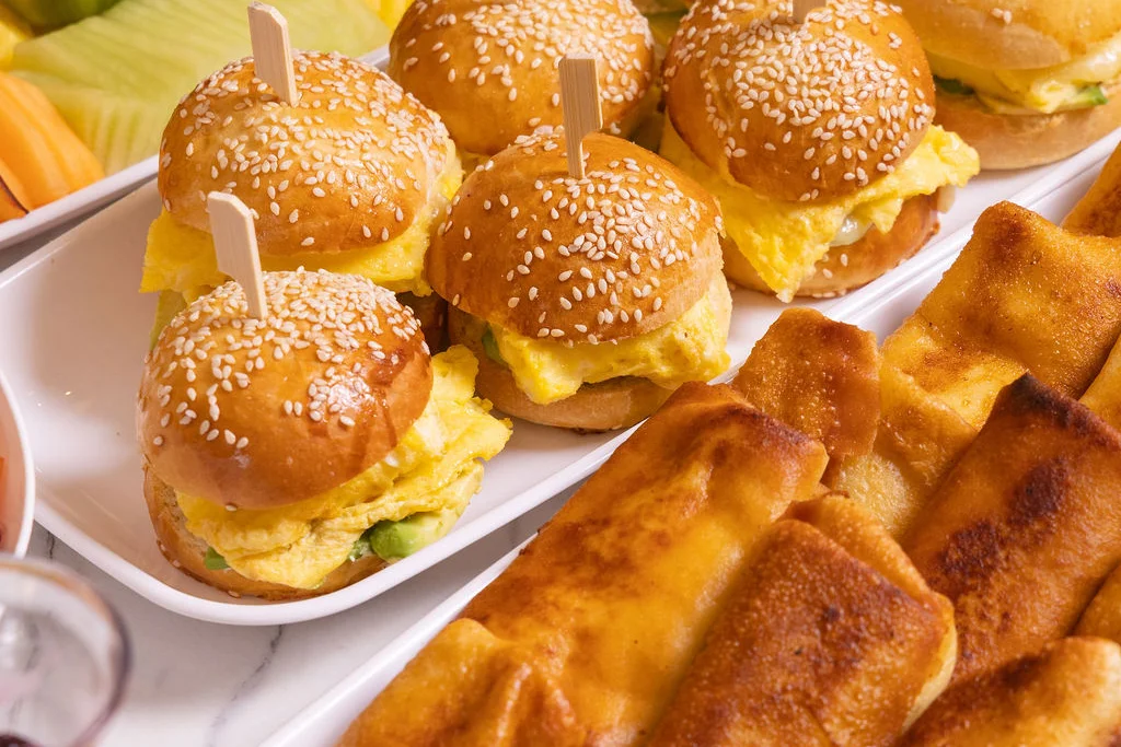 Assorted catering spread with churros, grilled skewers, and fresh salads