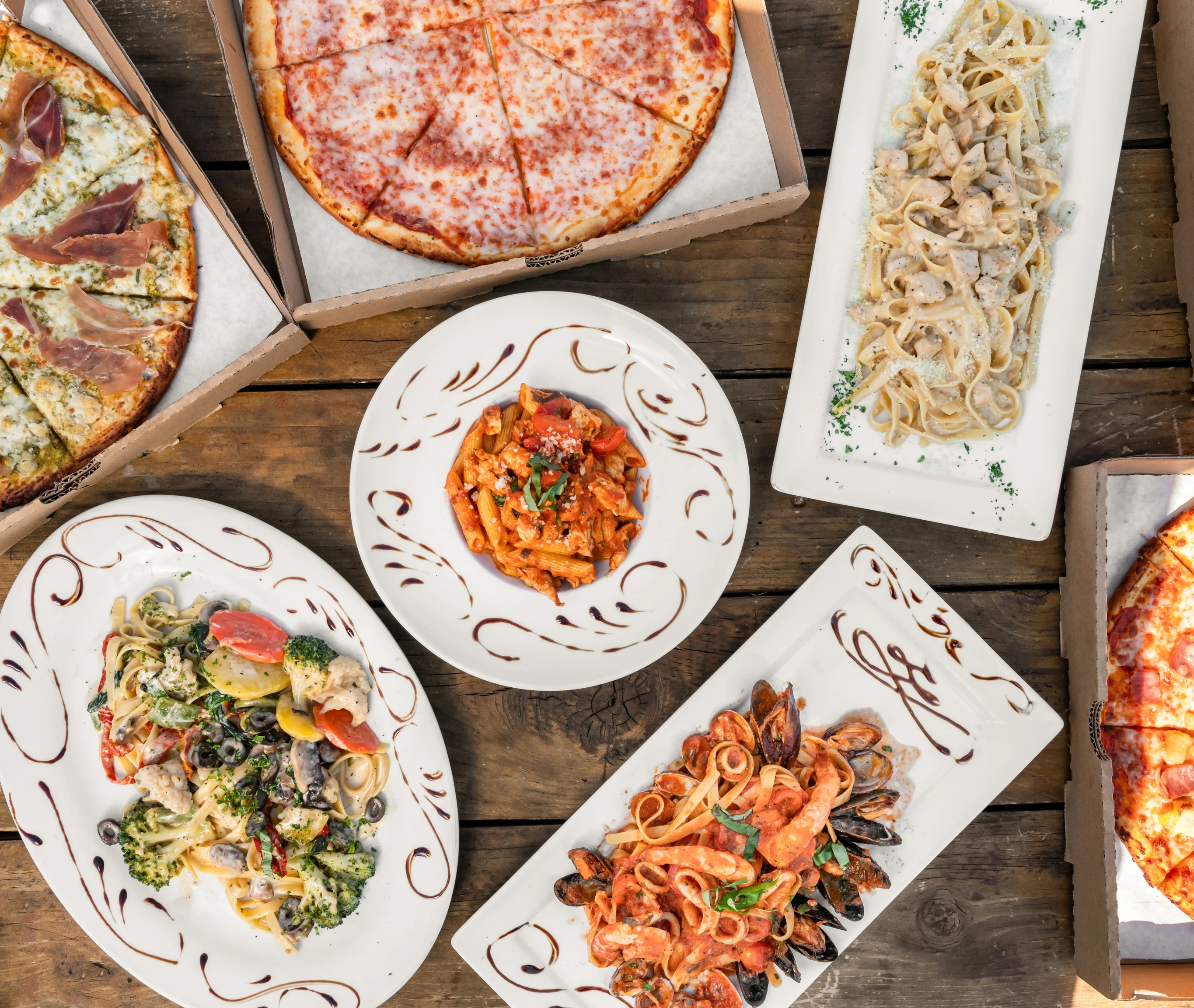 Italian pasta dishes and pizzas on a rustic wooden table
