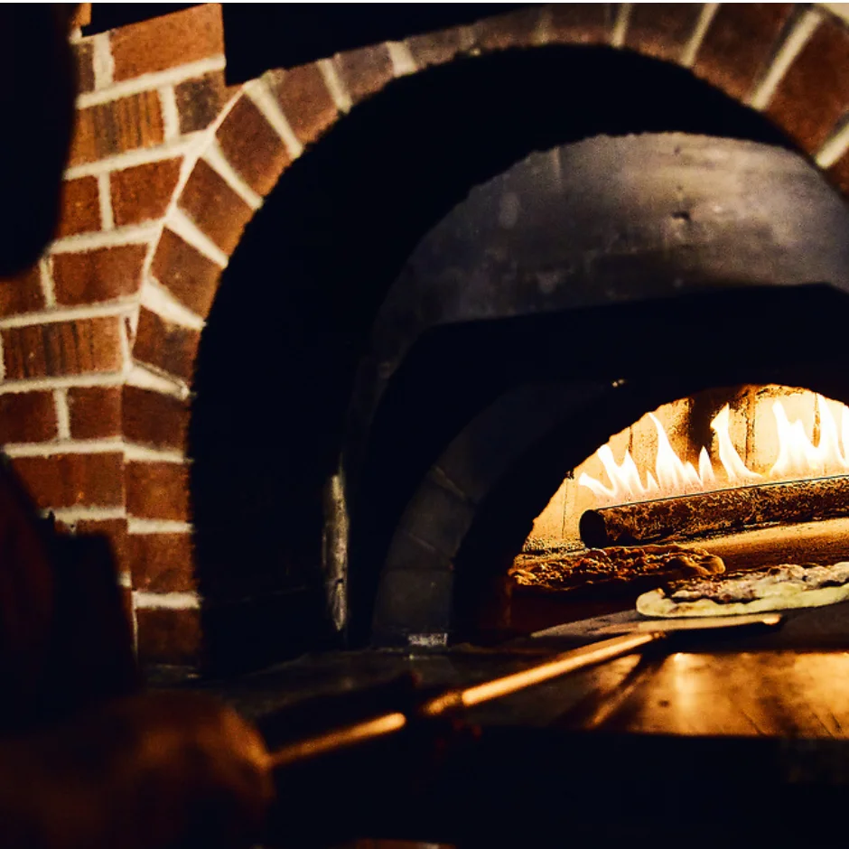 Wood-fired Margherita pizza baking in a traditional oven