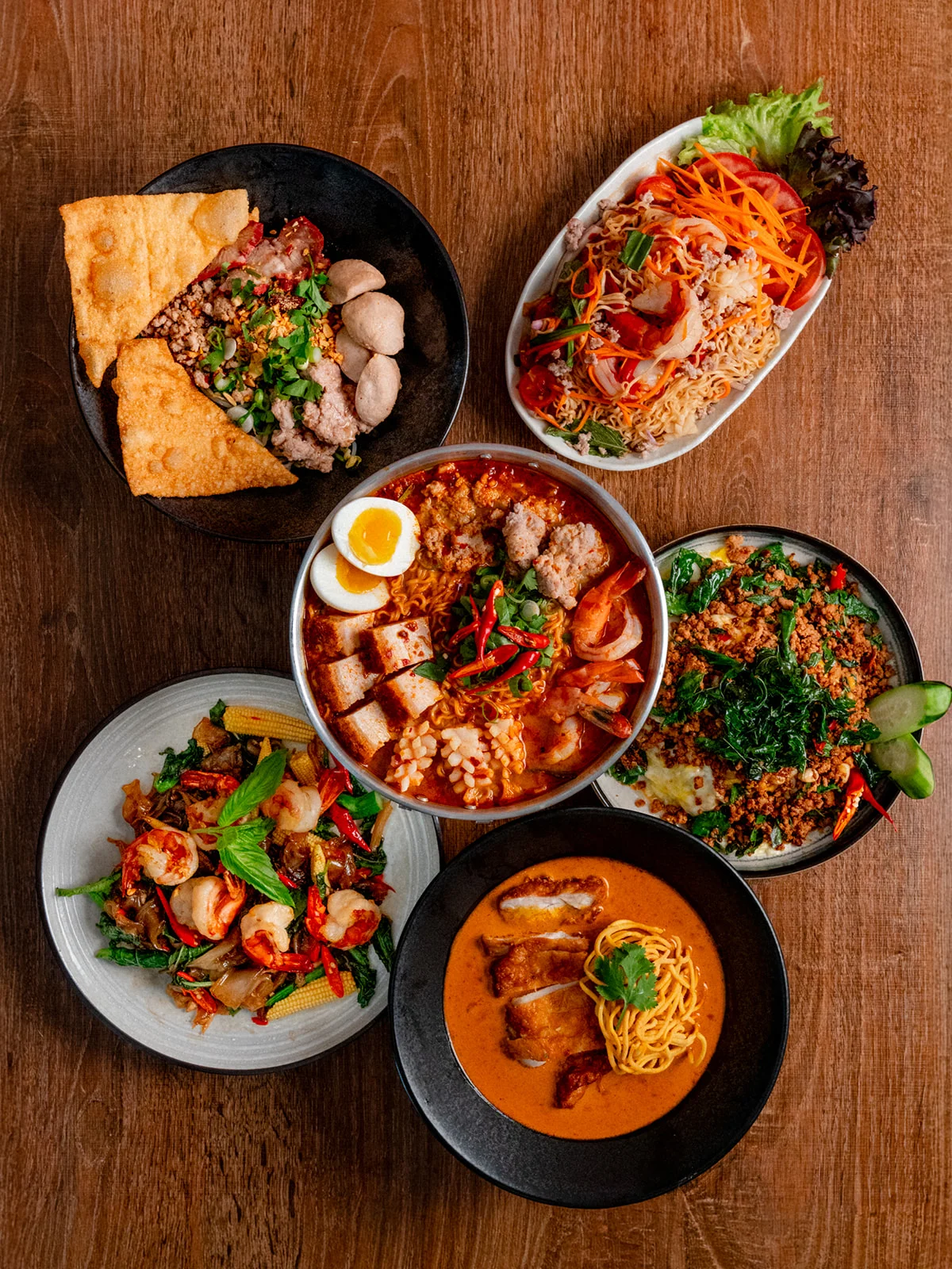 Three stacked white bowls with a logo for a Thai noodle house, featuring red lettering and a bowl illustration.