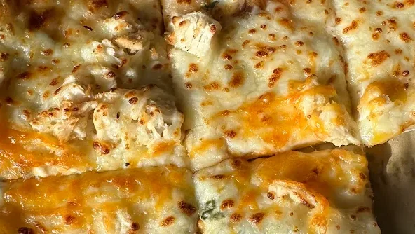 Close-up of cheesy pizza with golden crust and toppings.