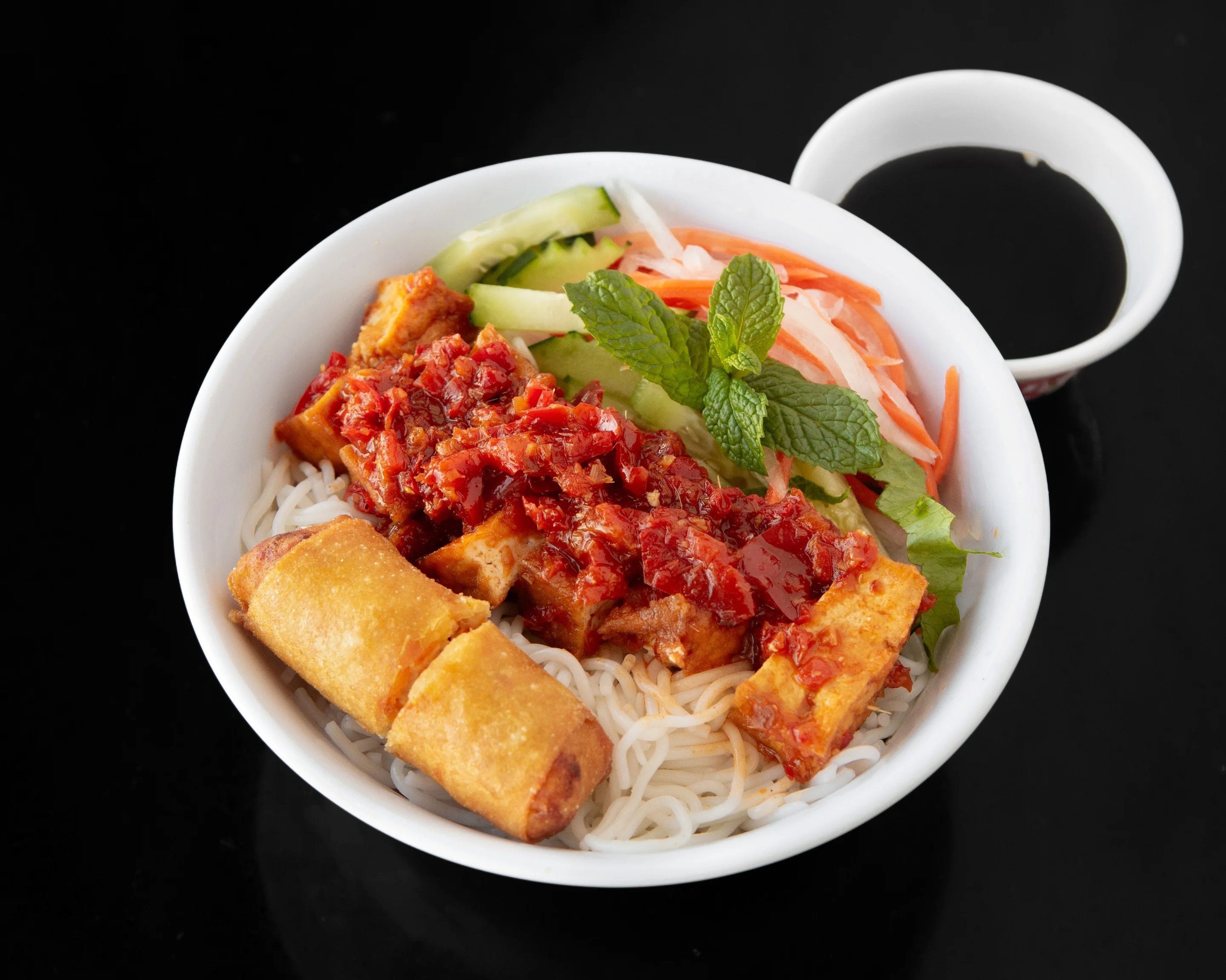 Vietnamese bun thit nuong with spring rolls and fresh herbs