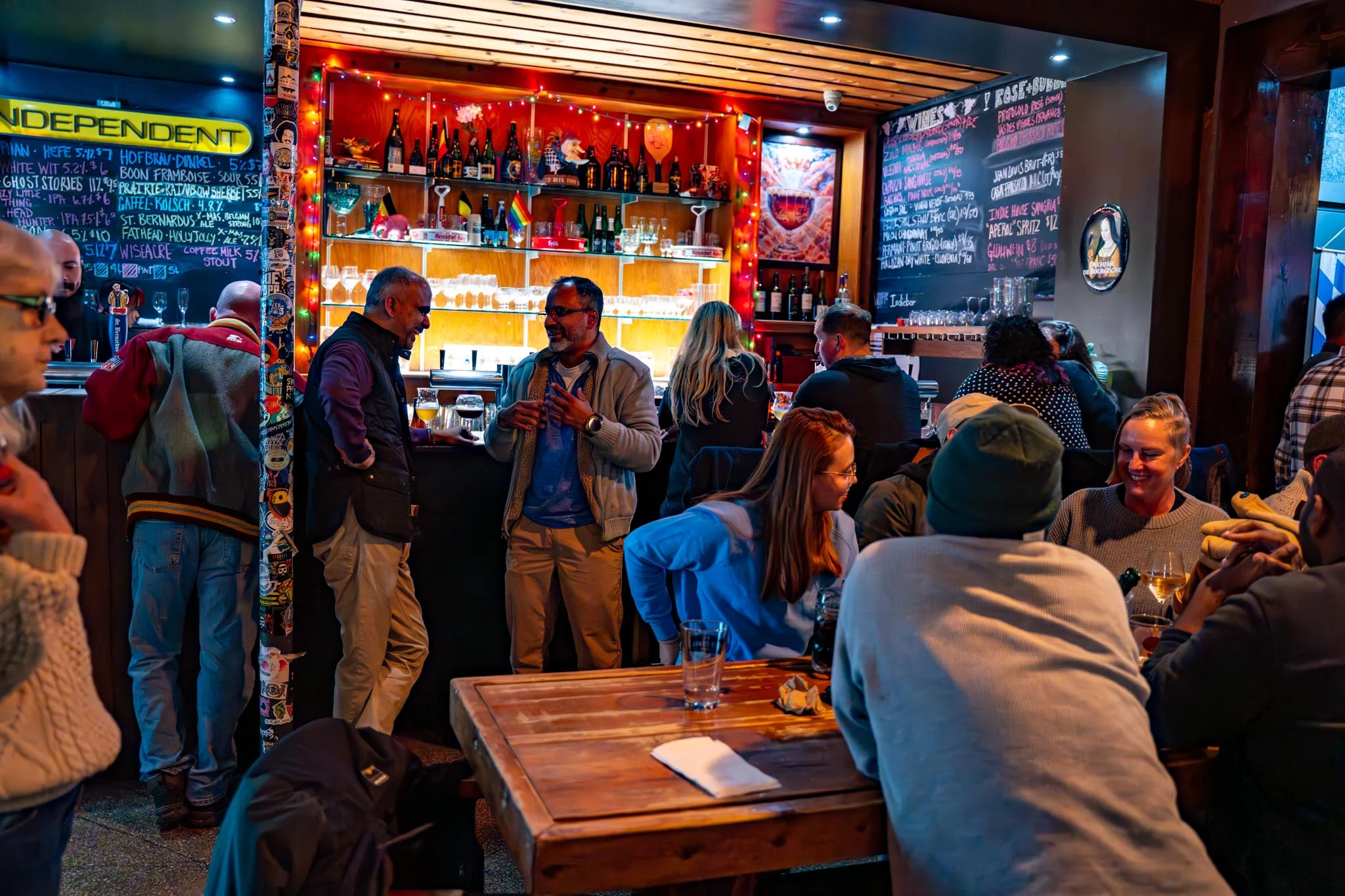 Lively bar scene with patrons enjoying drinks and conversation in a cozy setting.