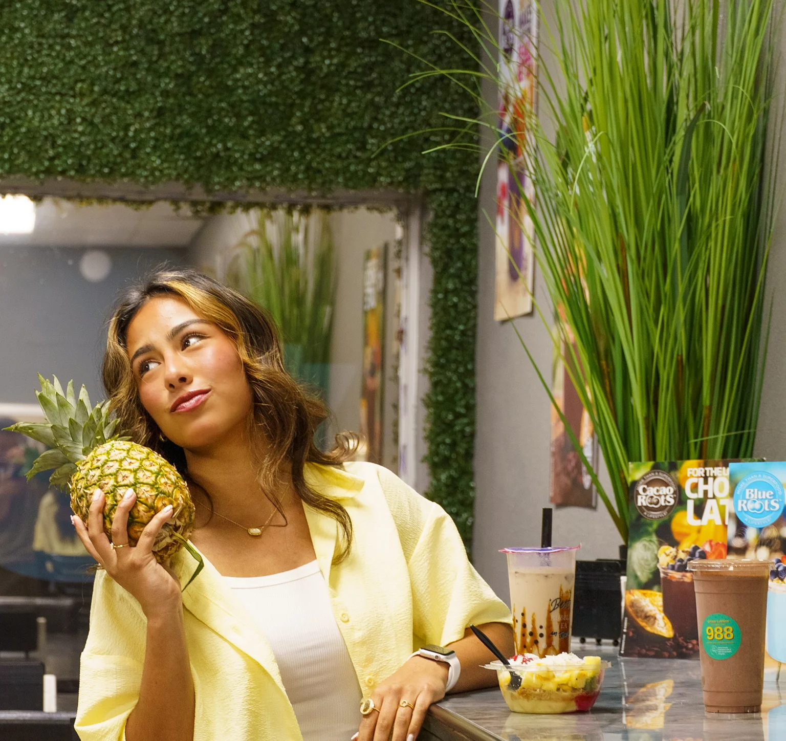 A woman enjoying a drink in a cozy restaurant setting with plants.