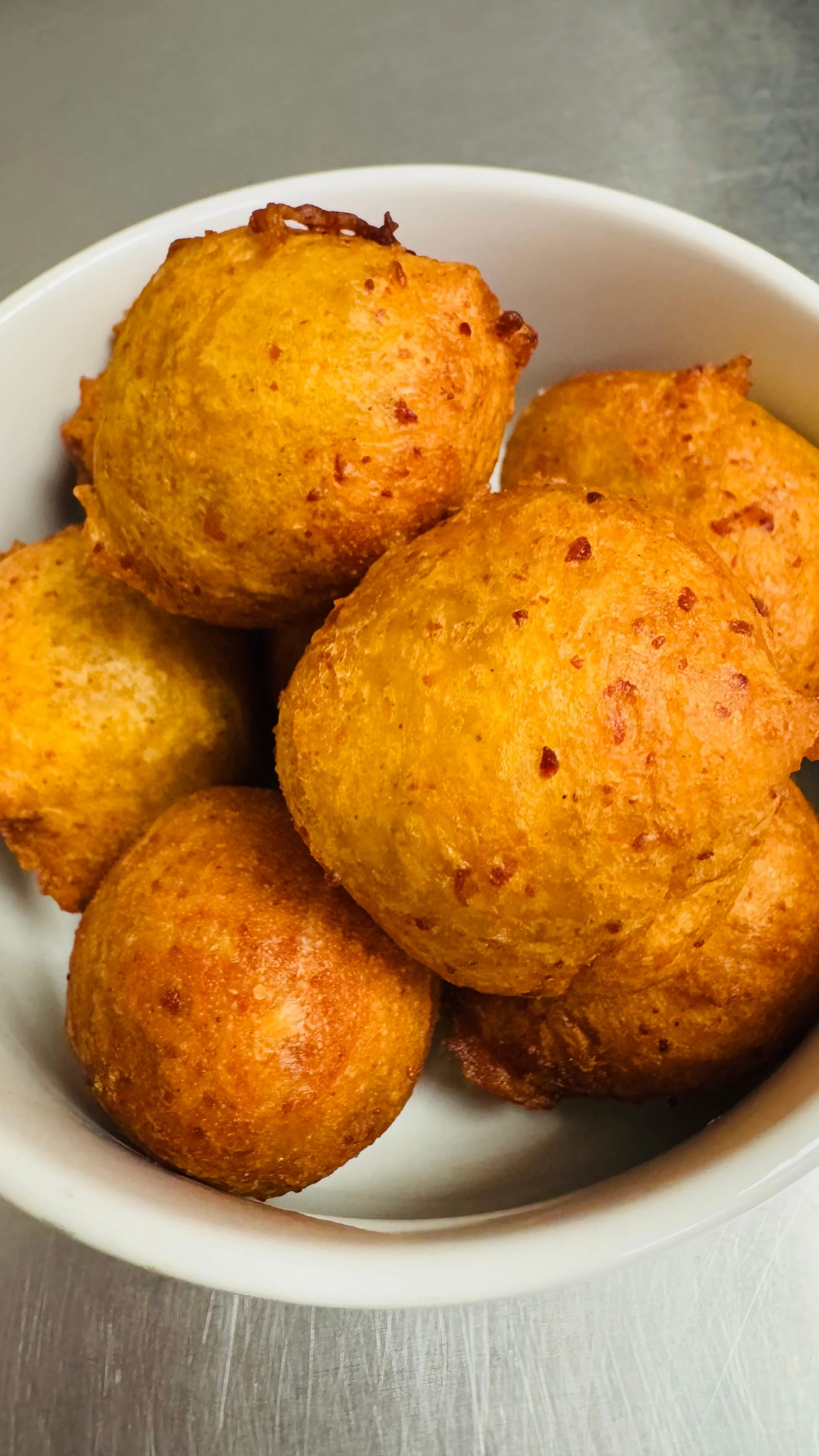 A bowl filled with golden-brown fried dough balls, showcasing a crispy exterior and fluffy interior.