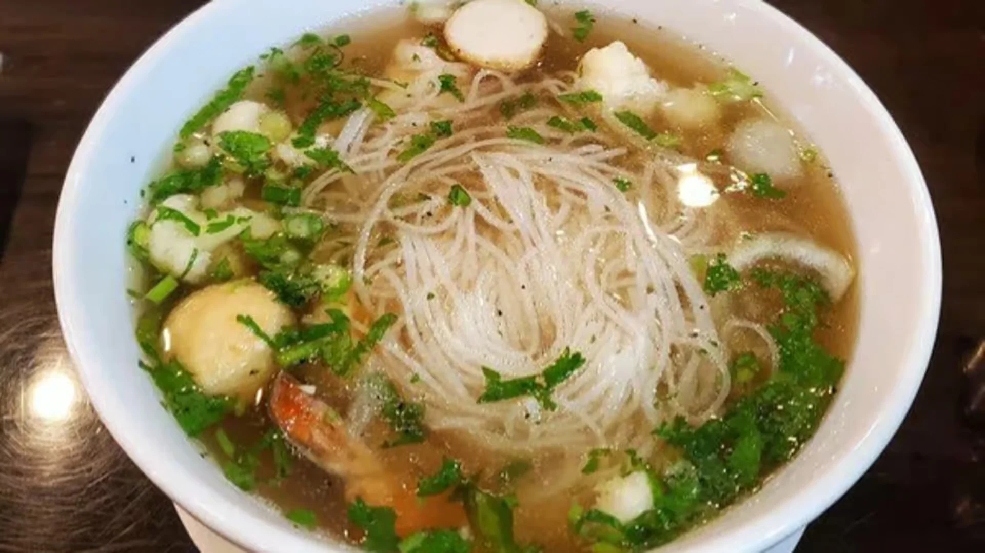 Bowl of Vietnamese bun rieu with herbs and noodles