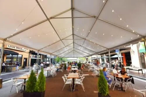 Outdoor dining area under a large tent with string lights