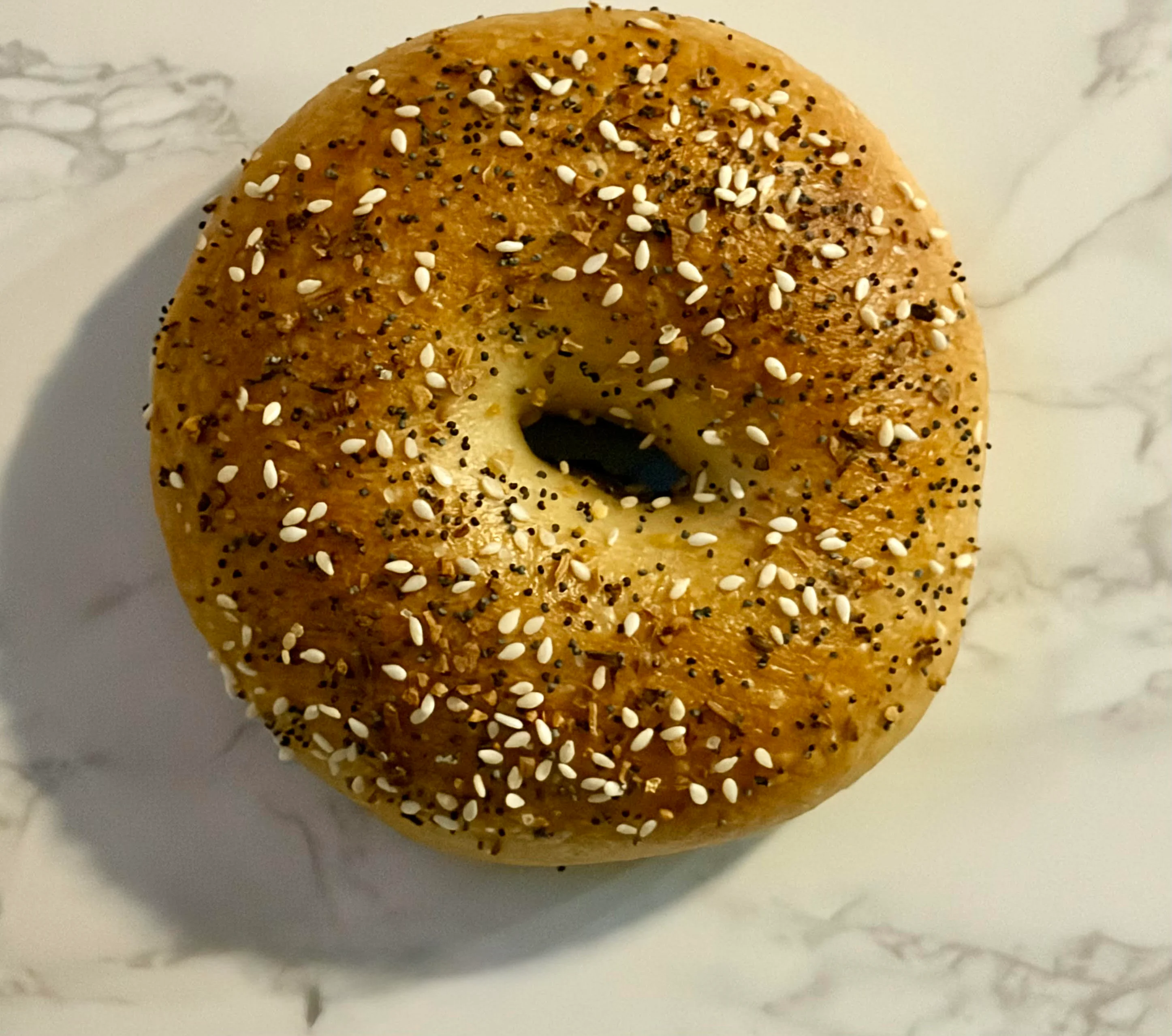 A freshly baked bagel topped with sesame and poppy seeds.