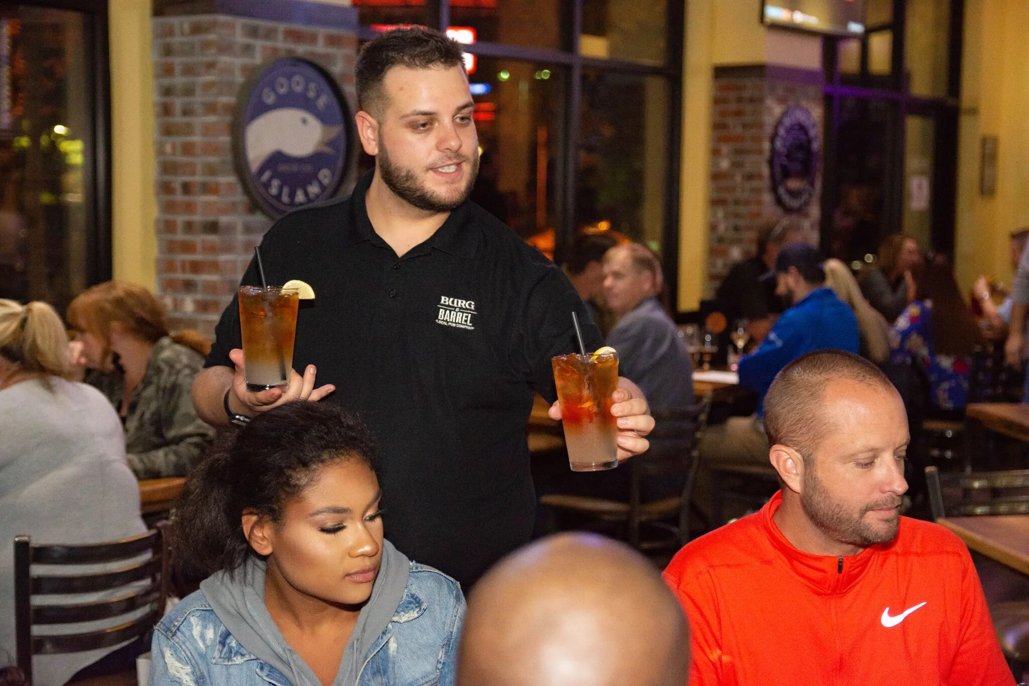 Server presenting cocktails in a lively restaurant setting