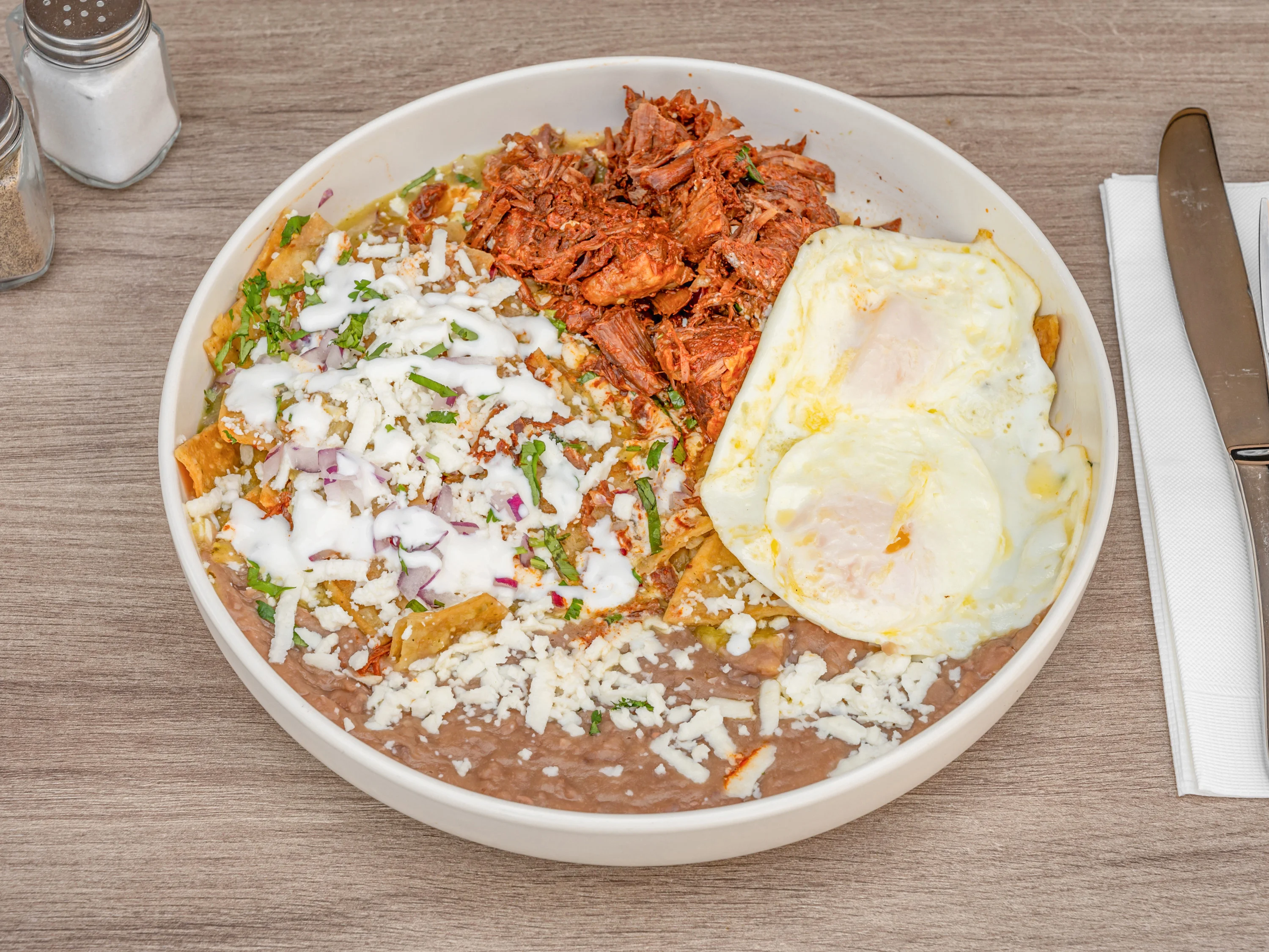 Plate of Mexican chilaquiles with eggs and shredded meat