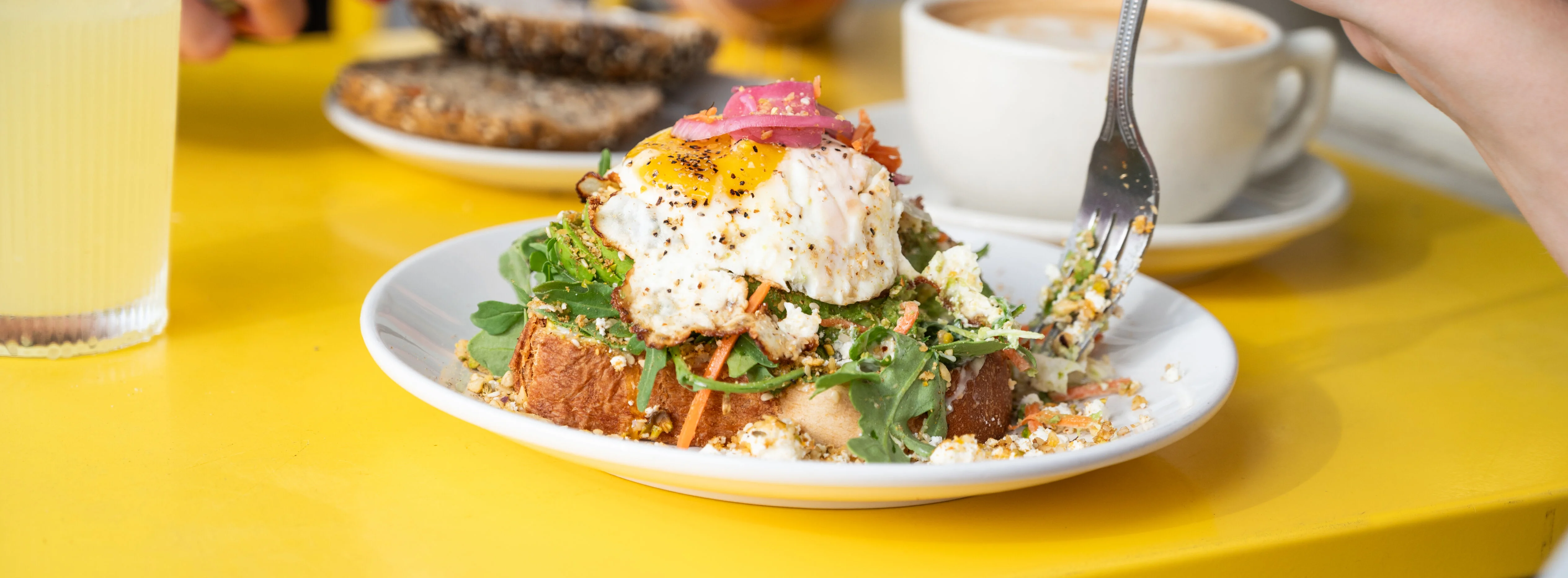 Avocado toast topped with poached egg and greens