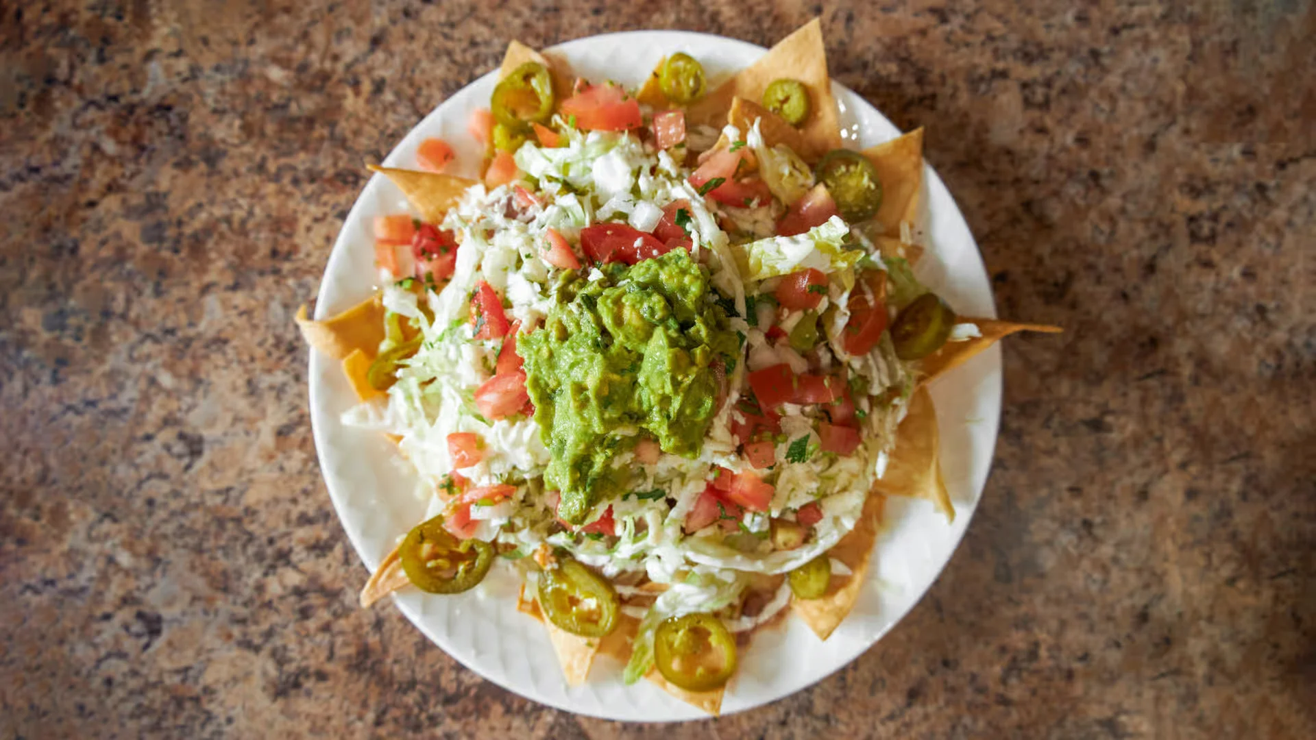  A shareable plate of loaded nachos from El Ranchito Poblano in Brooklyn, topped with fresh guacamole and jalapeños.