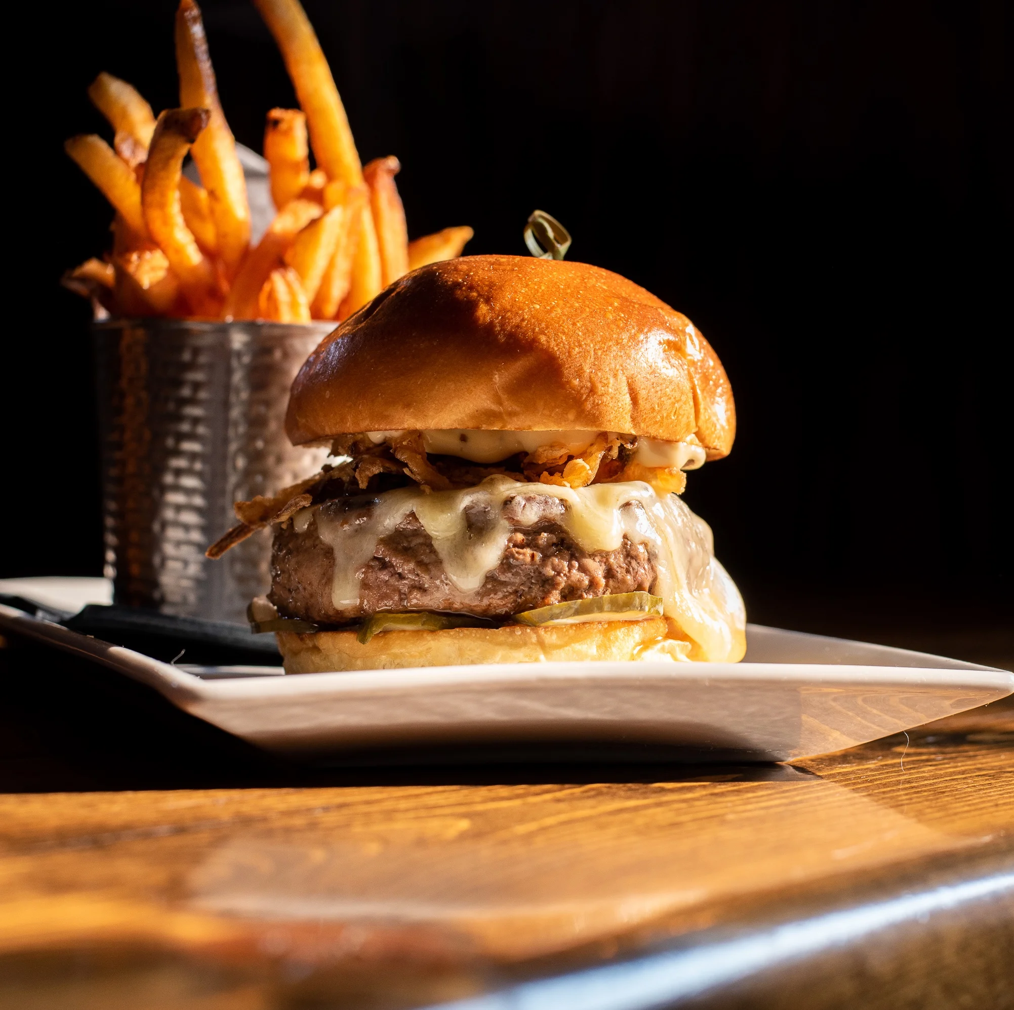 Juicy American cheeseburger with crispy fries on a wooden table