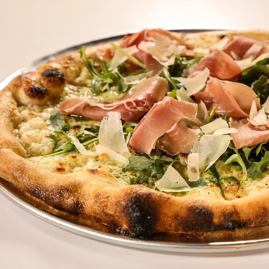 Prosciutto pizza with arugula and cheese