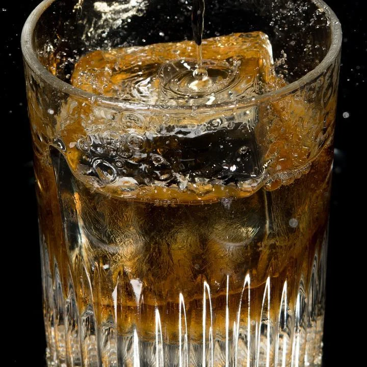 Whiskey cocktail splashing in a glass with ice