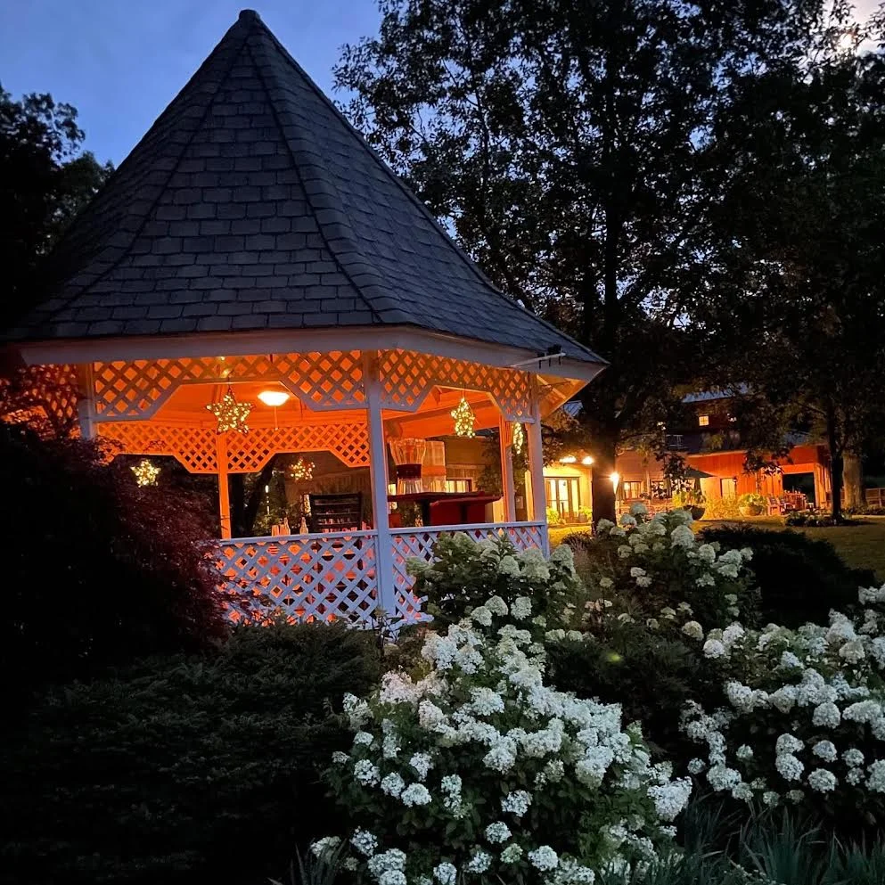 Charming gazebo illuminated at dusk surrounded by blooming flowers