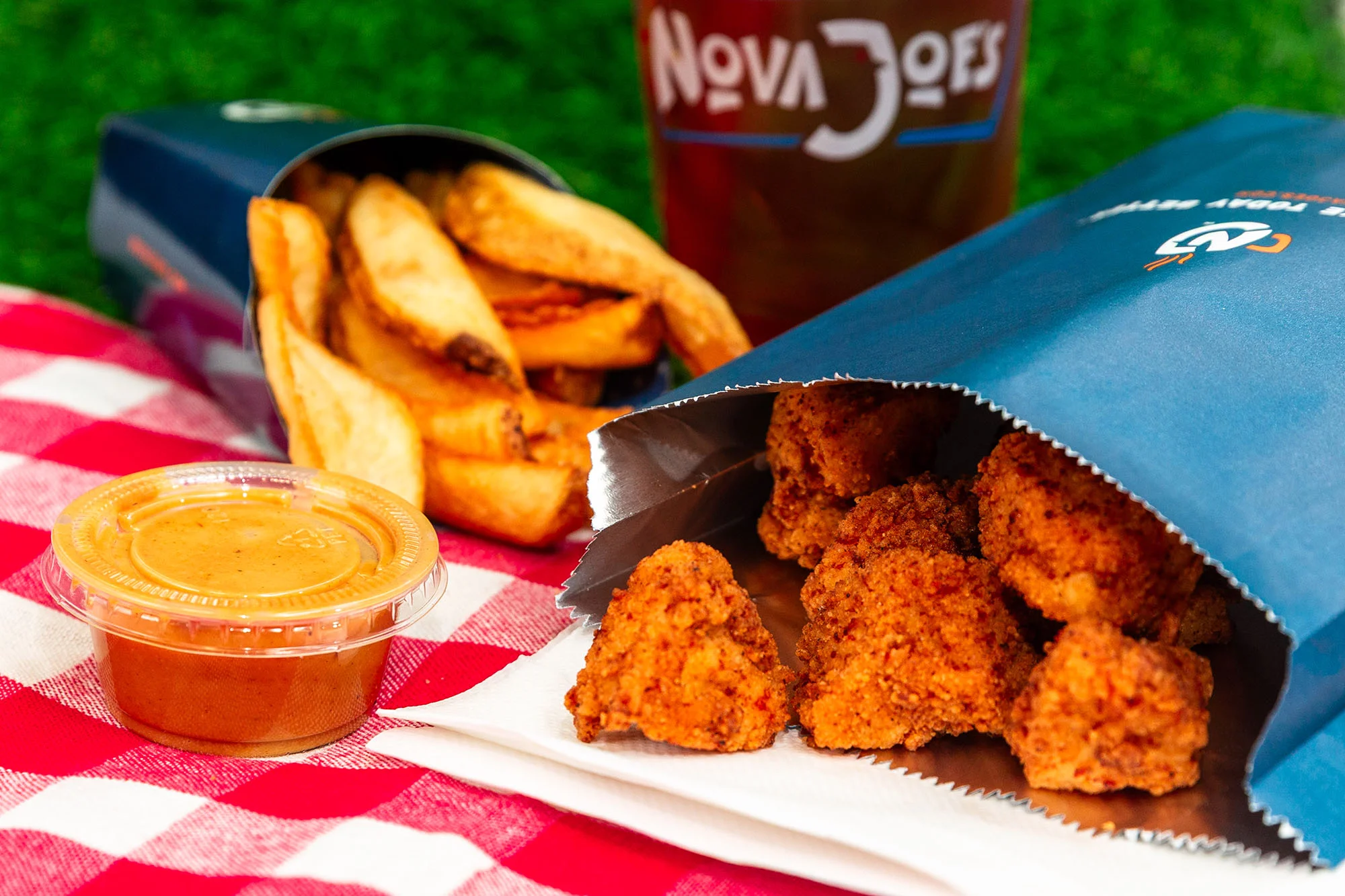A picnic lunch of chicken nuggets, fries, sauce and a drink.