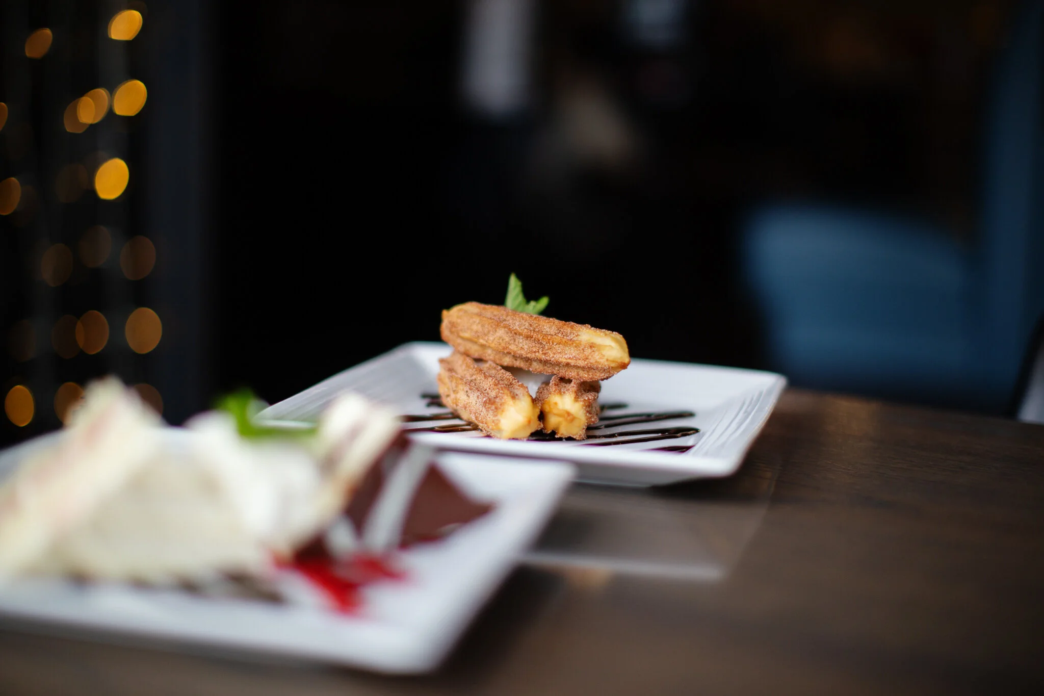 Churros served with chocolate sauce in a modern restaurant setting