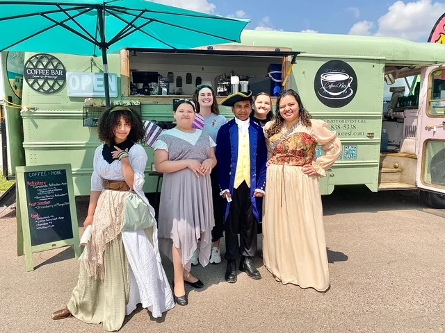 Group of staff in historical costumes at a coffee truck