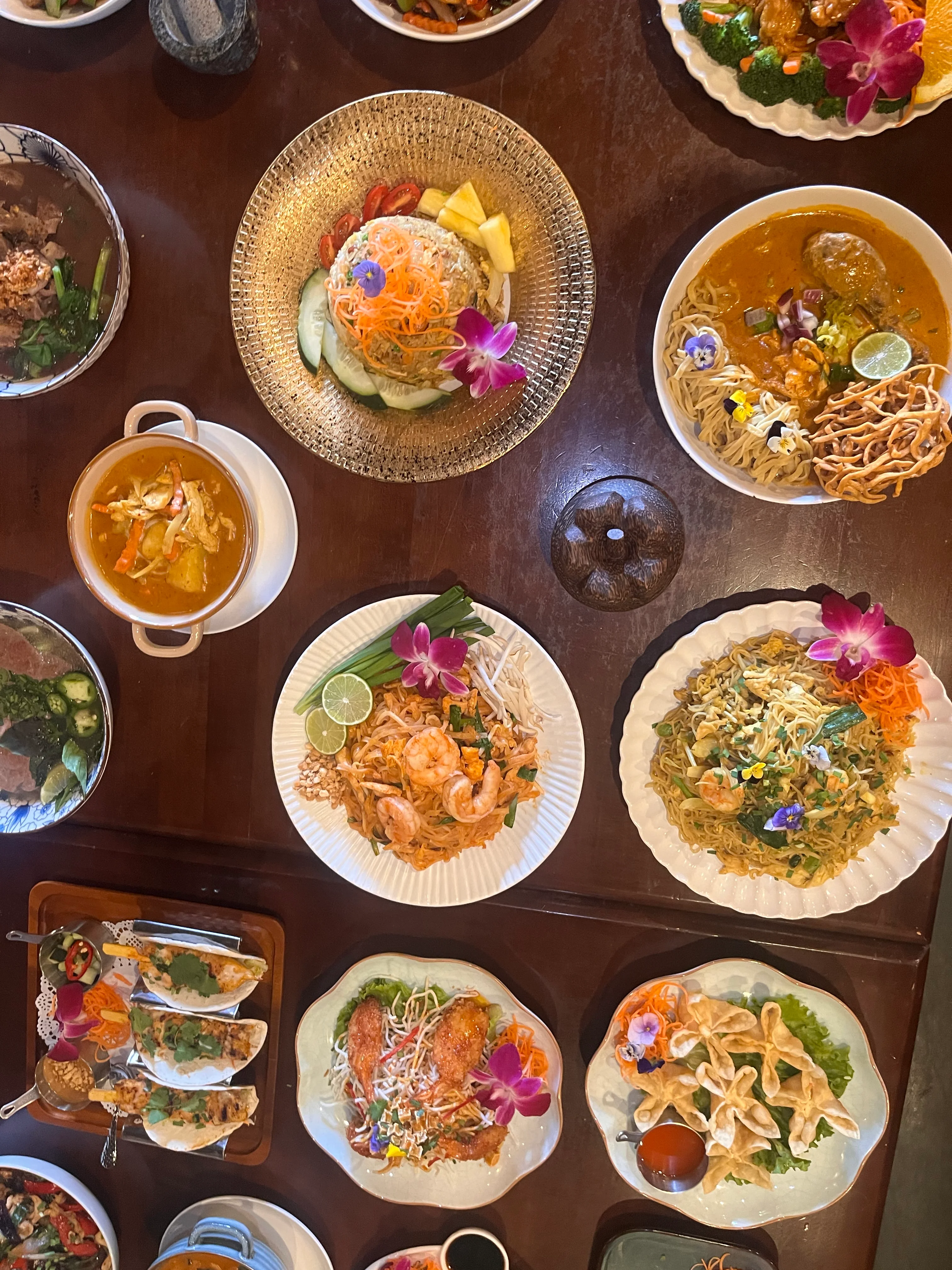 Assorted Thai dishes including pad thai and curry on a wooden table