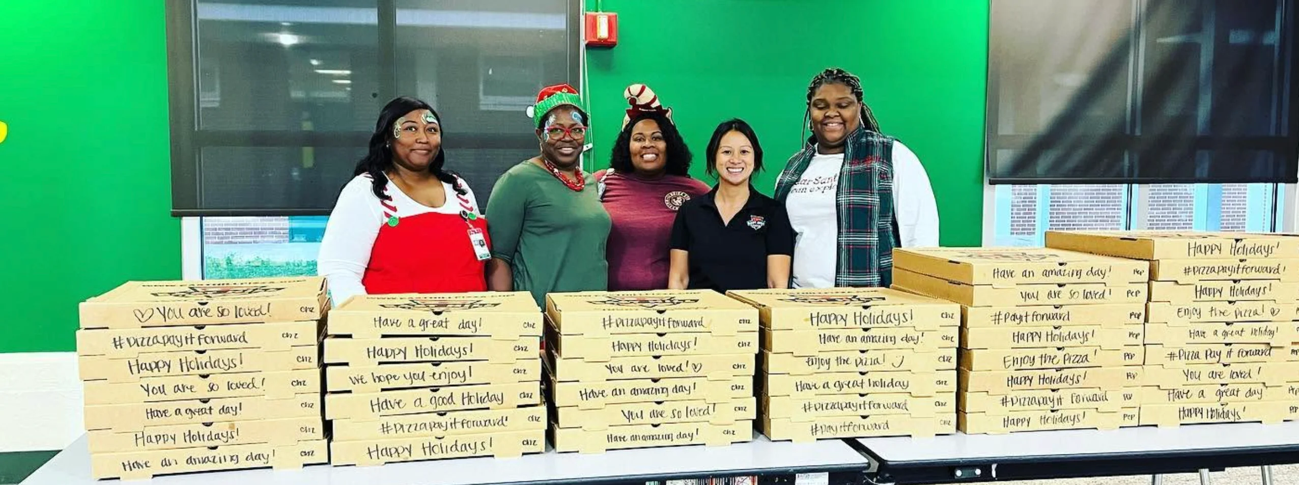 Restaurant team posing behind stacks of holiday pizza boxes