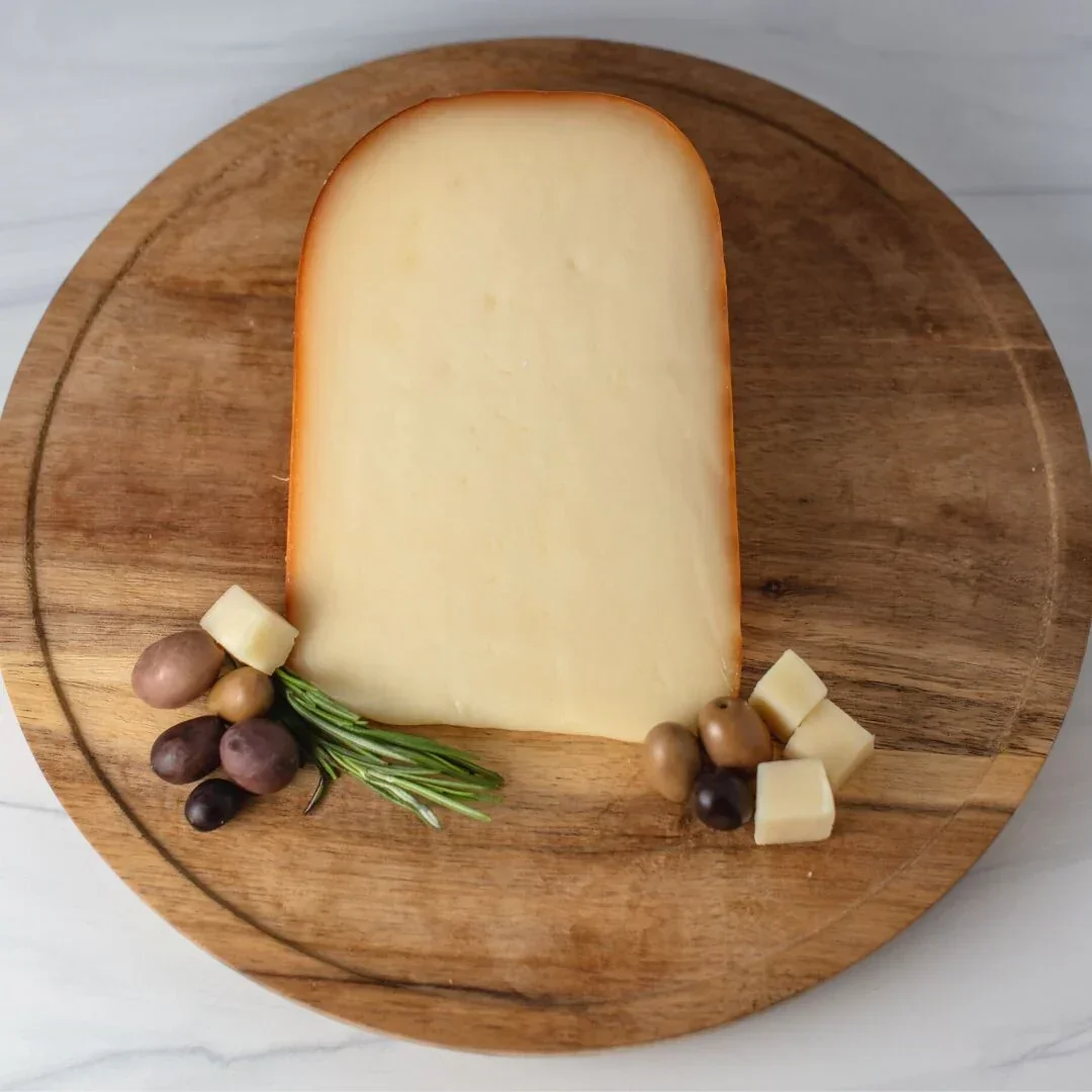 Artisan cheese on a wooden board with olives and rosemary