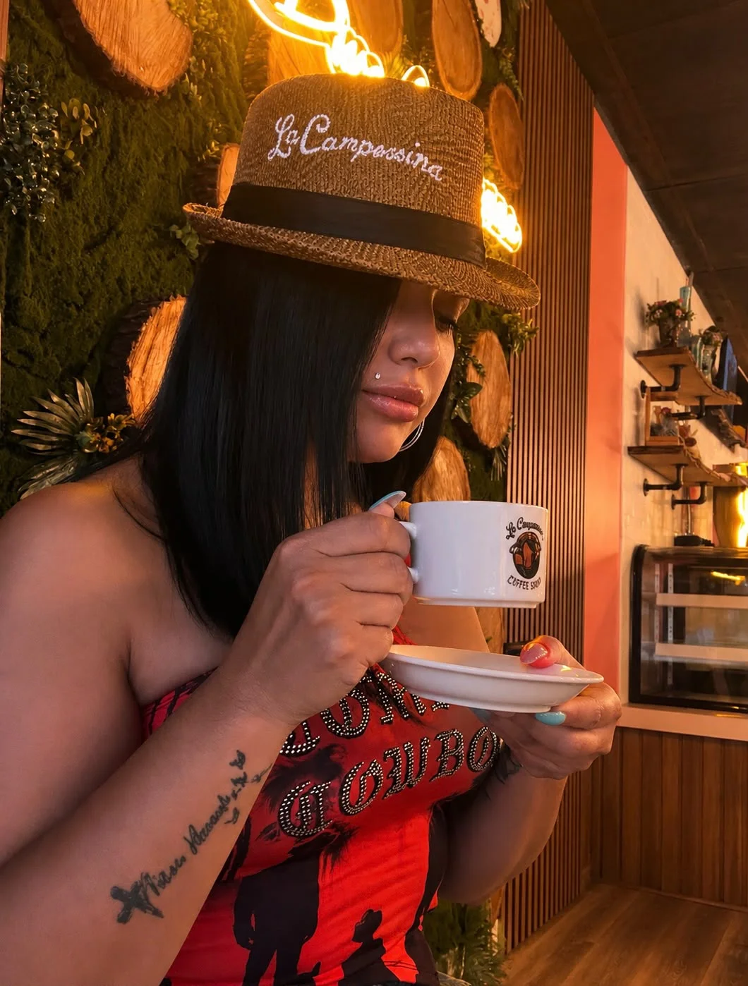 A woman in a straw hat savoring a cup of coffee while surrounded by a rustic cafe atmosphere with wood accents.