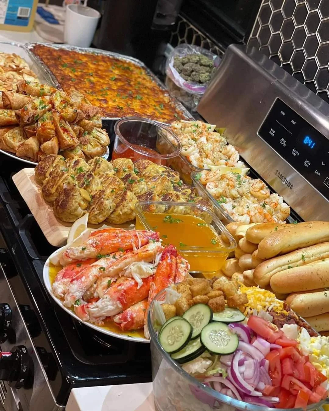 A large spread of various dishes including shrimp, breadsticks, and salads, presented on a kitchen counter.